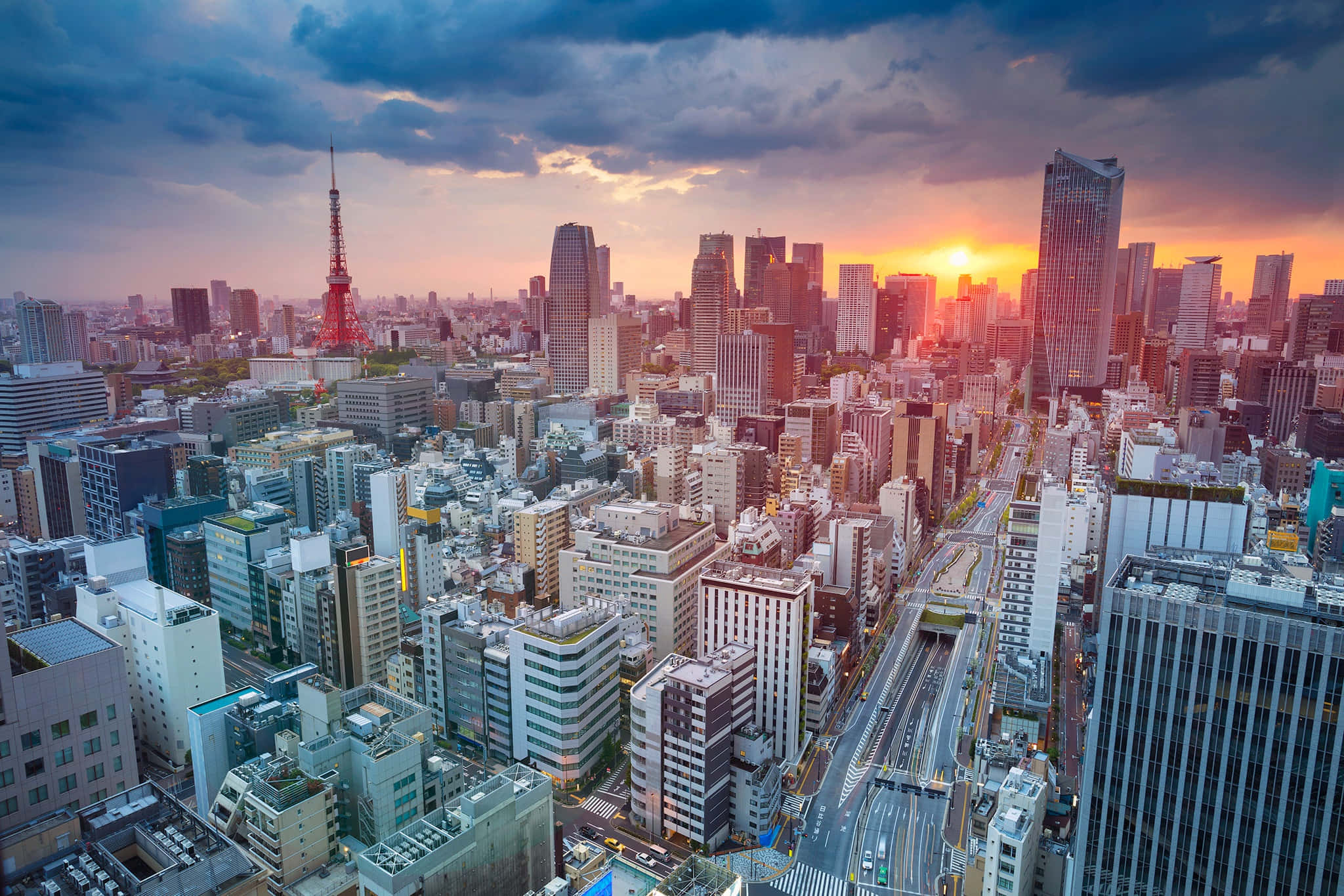 東京 桌布 壁紙 — 日落時分東京天際線的鳥瞰圖，充滿活力的橙色光芒照亮了摩天大樓和標誌性的紅色東京塔。