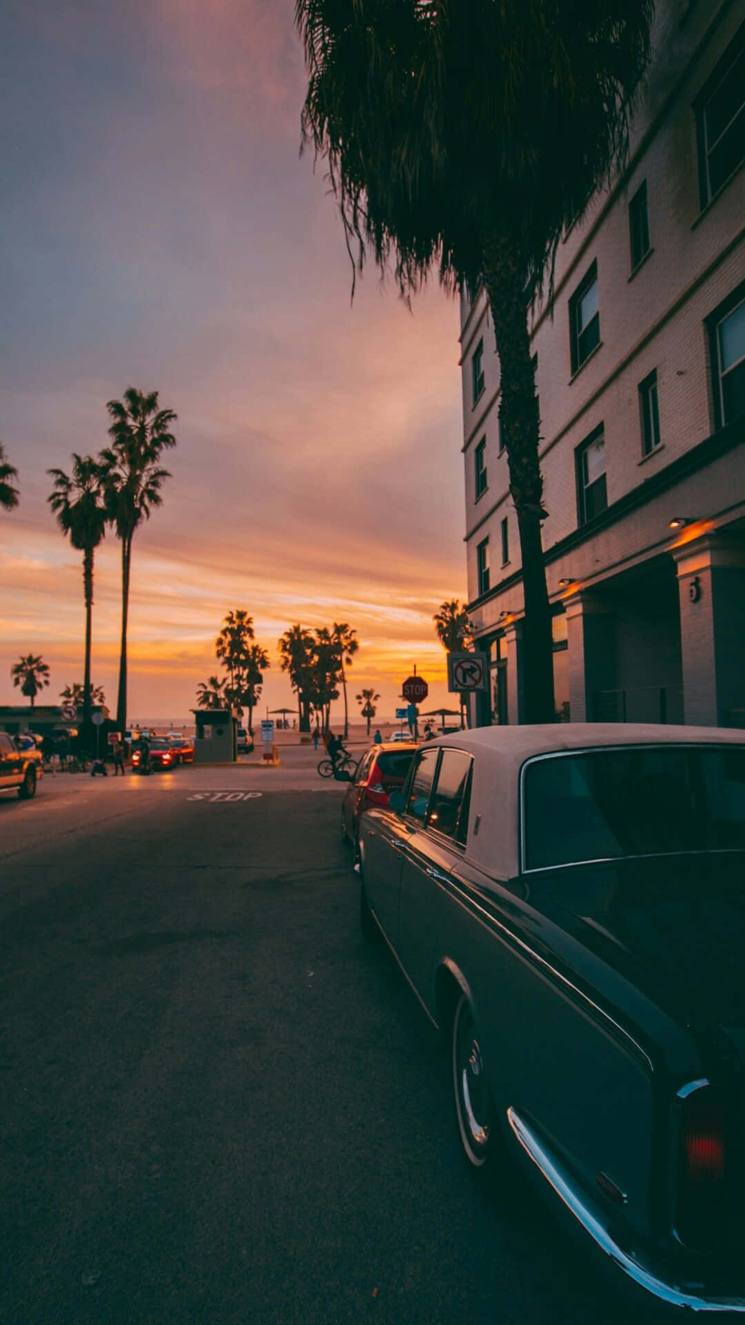 復古車停在有棕櫚樹和夕陽天空的街道上
