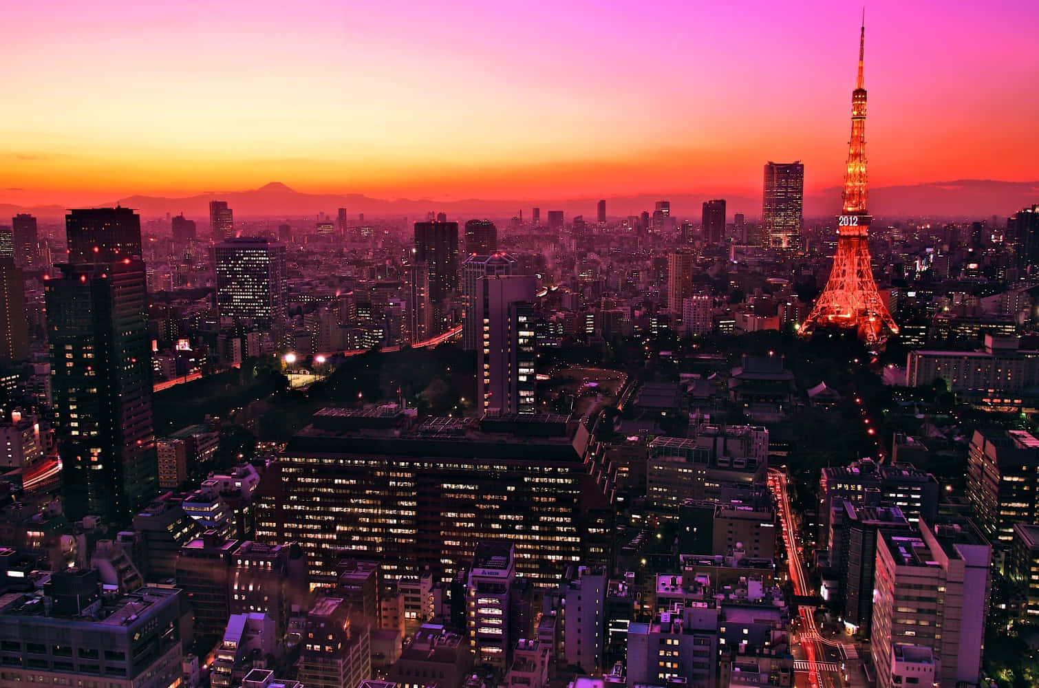 東京 桌布 壁紙 — 日落時分的東京天際線，閃耀的東京塔和遠處的富士山在火紅的橙色和粉紅色天空下。