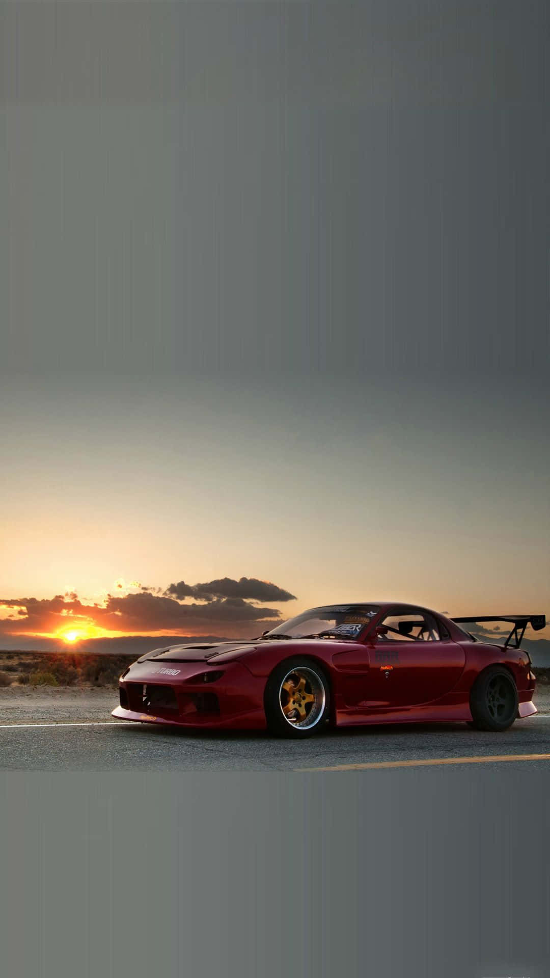 紅色Mazda RX-7跑車停泊在日落時分的沙漠道路上。