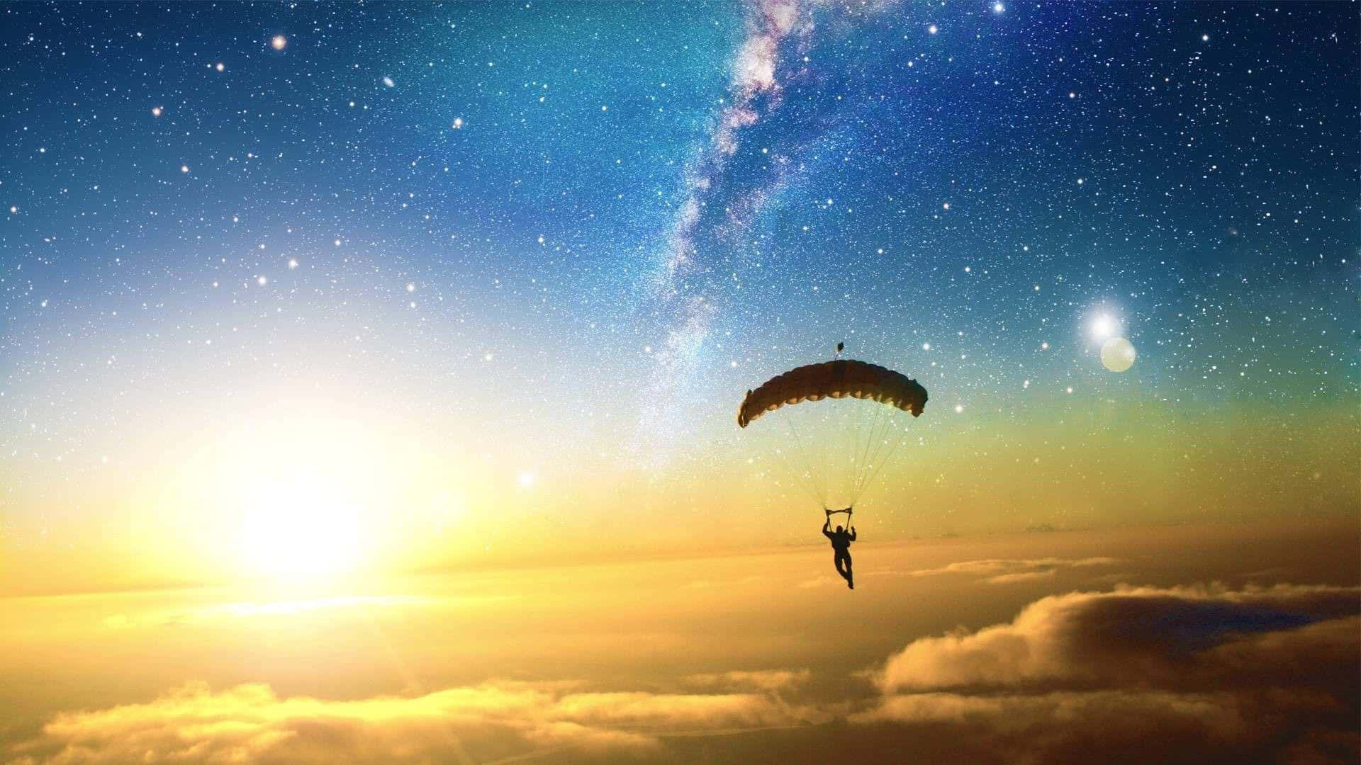 跳傘運動員在日落時漂浮在雲層之上，星星和銀河可見。