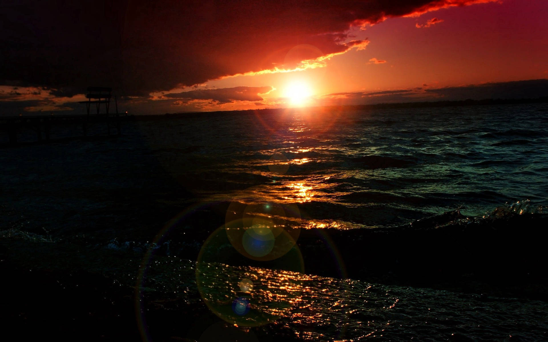 夕陽映照海面，帶有鏡頭光暈和碼頭剪影
