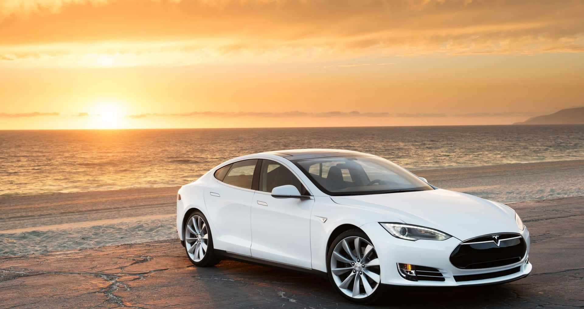白色Tesla汽車停泊在沙灘上，金色夕陽下海浪翻滾。