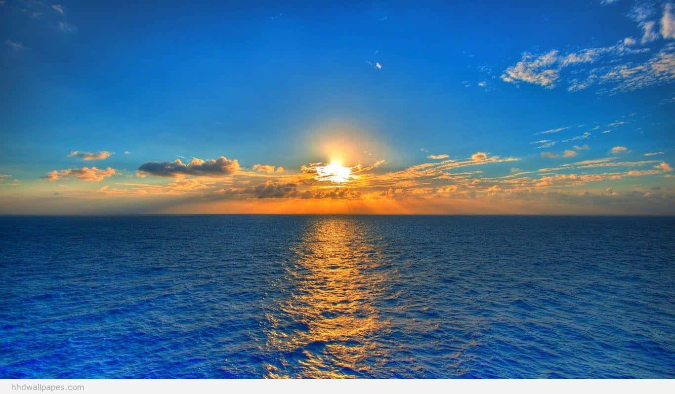 平靜海面上的日落，金色倒影和散落的雲朵。