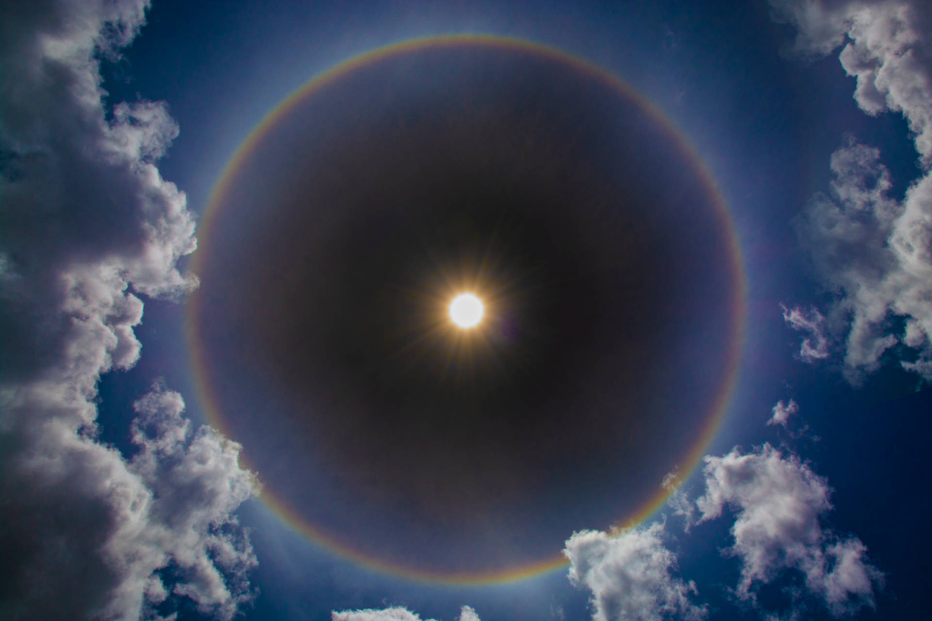 太陽帶有彩虹光環和白雲在藍天中