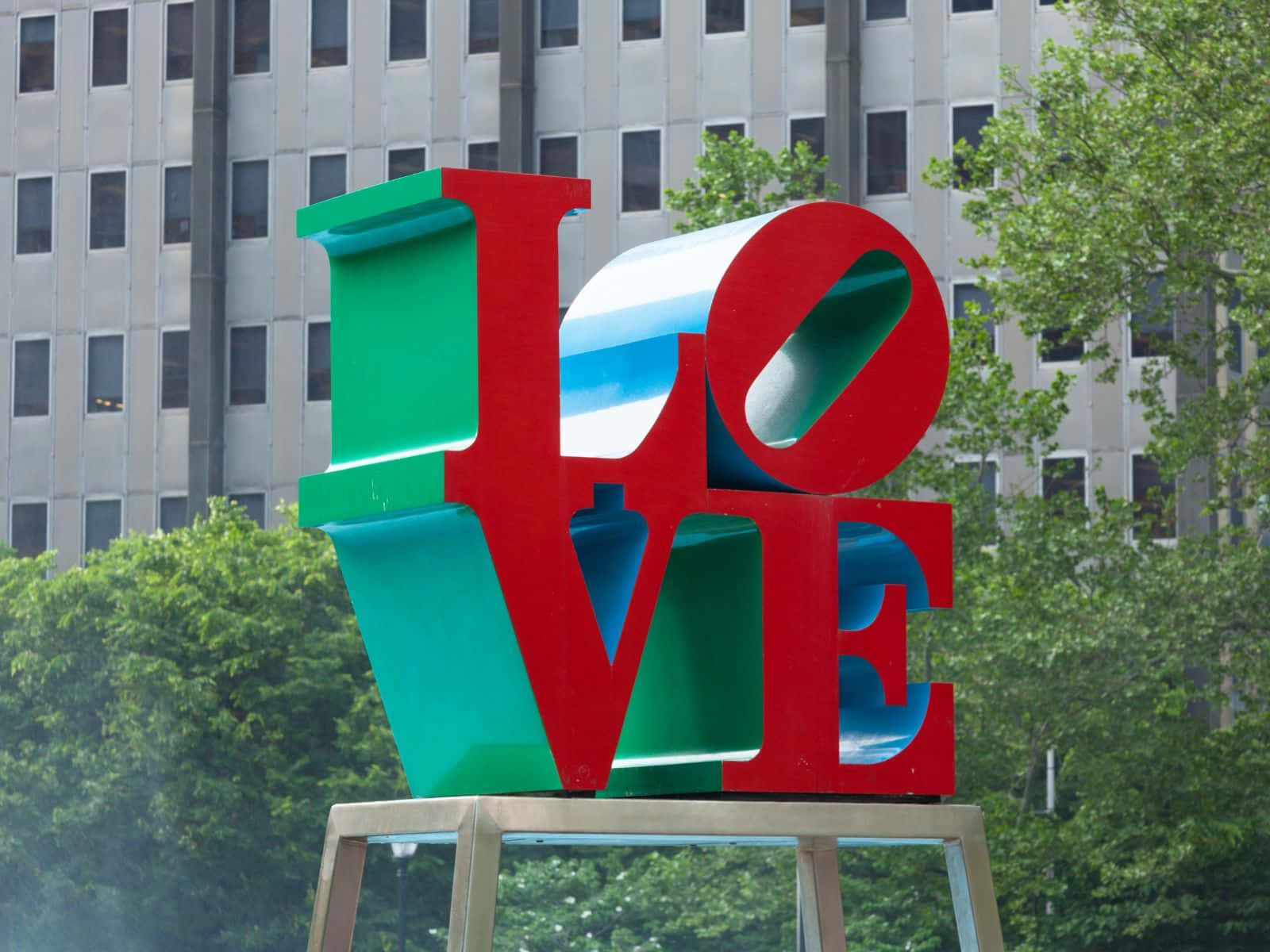 城市公園中色彩繽紛的LOVE雕塑，背景有樹木和建築物