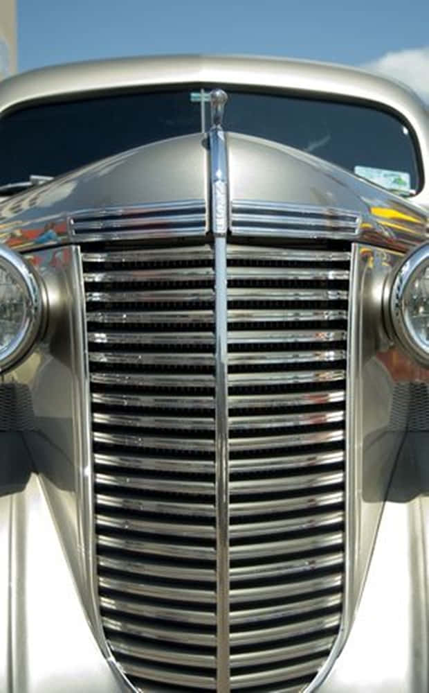 Car Grill 桌布 壁紙 — 明亮日光下經典汽車閃亮鍍鉻格柵和引擎蓋飾件的特寫。