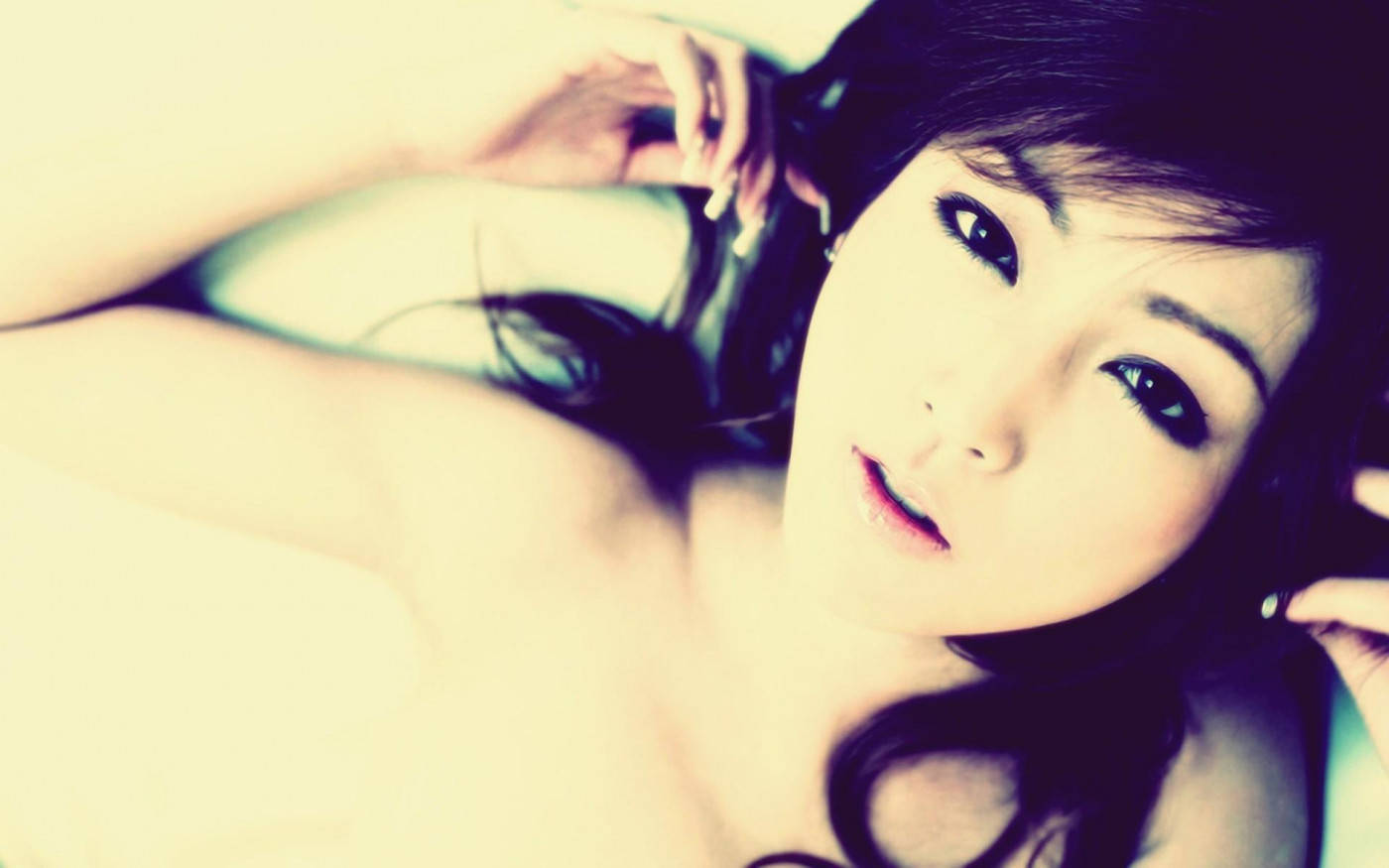 明亮濾鏡的態度女孩 壁紙 — 一位深色頭髮、眼神銳利的女性躺在柔和溫暖的光線中向上凝視。