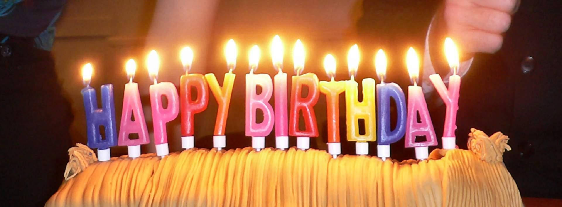 一個生日蛋糕，上面有點燃的蠟燭拼出 happy birthday。