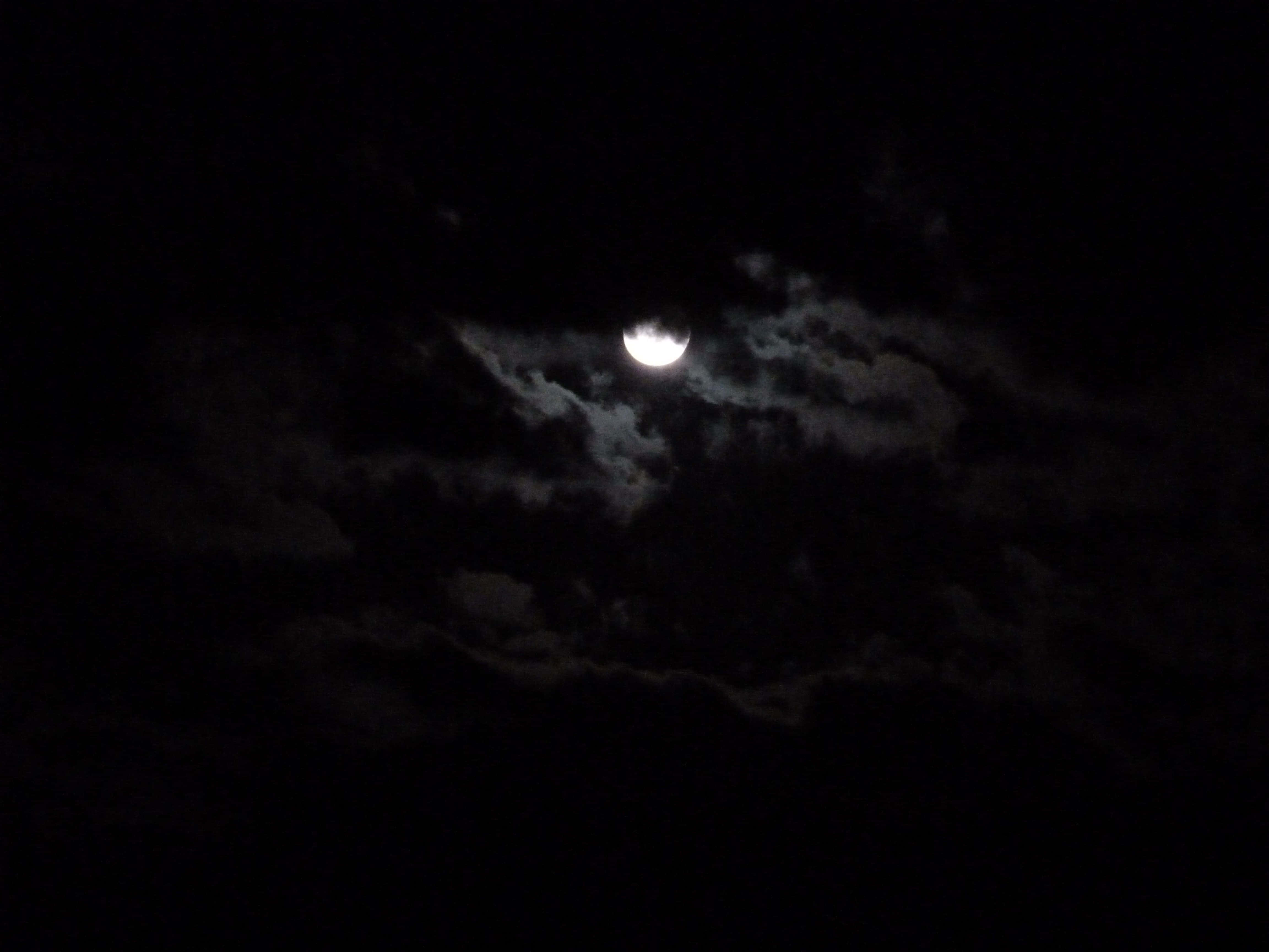 Dark Moon 桌布 壁紙 — 明亮的彎月穿過縷縷雲層，在黑暗的夜空中閃耀。