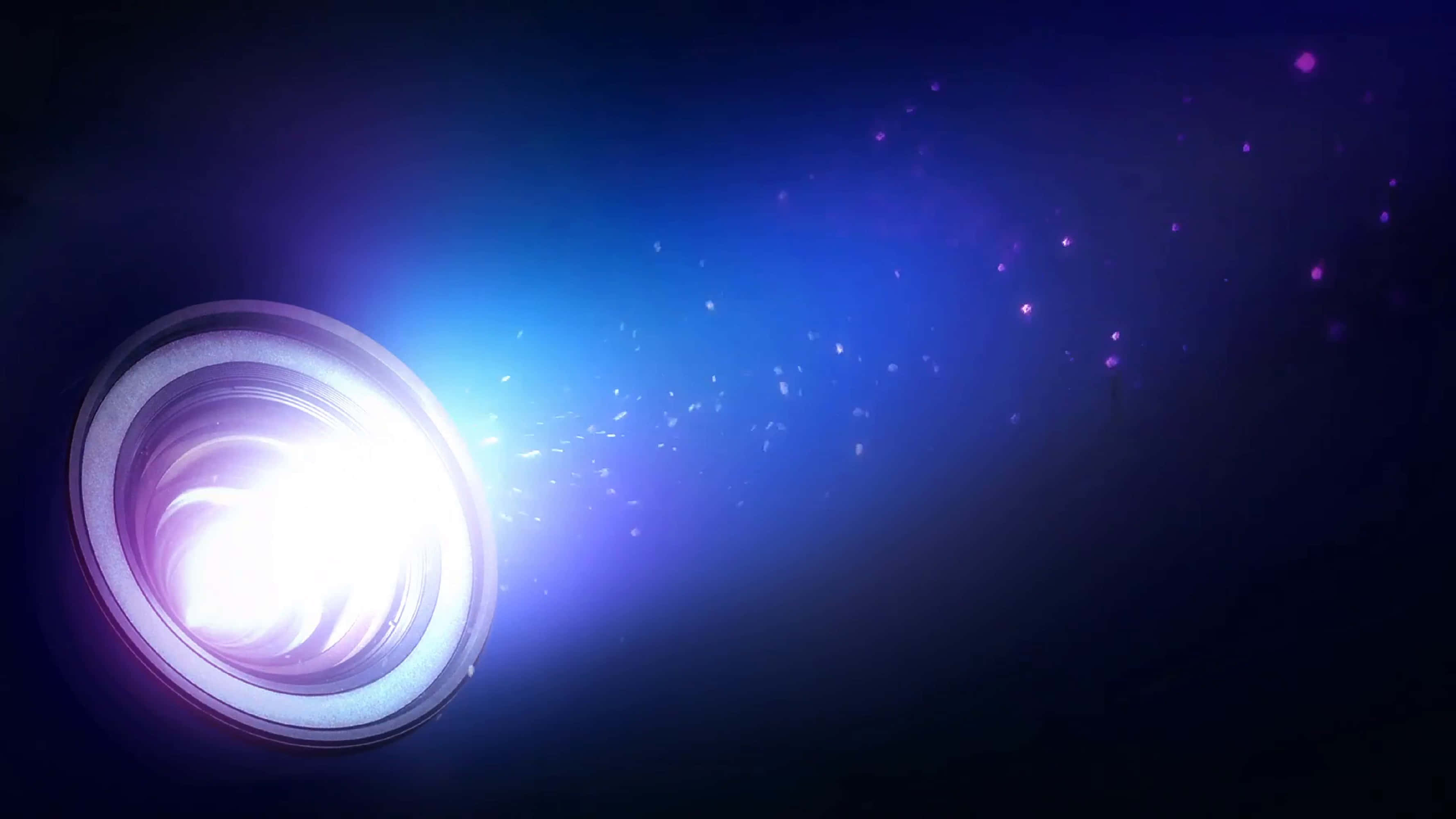 4K Projector 桌布 壁紙 — 明亮的投影機鏡頭在黑暗空間中發出燦爛的藍色光束，沿途散發發光粒子。