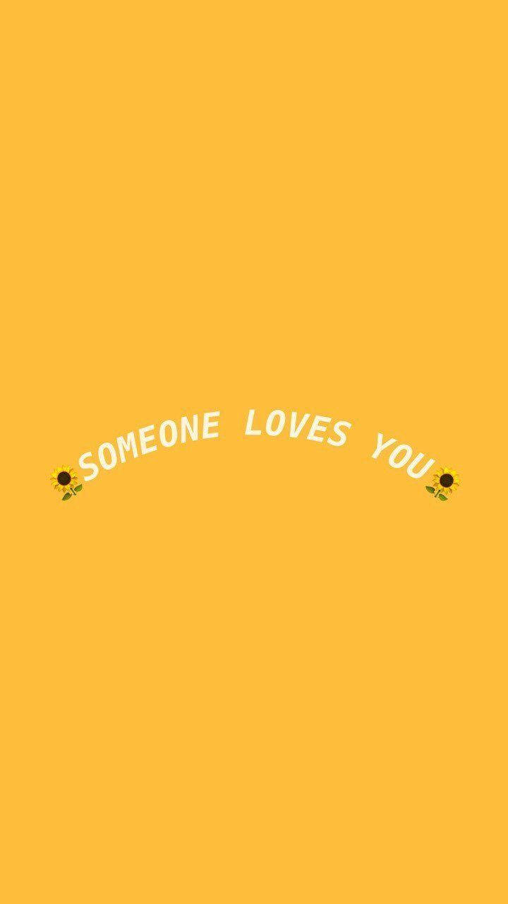 黃色美學 桌布 壁紙 — 明亮的黃色背景上，白色文字「someone loves you」在兩個向日葵表情符號之間呈拱形排列。