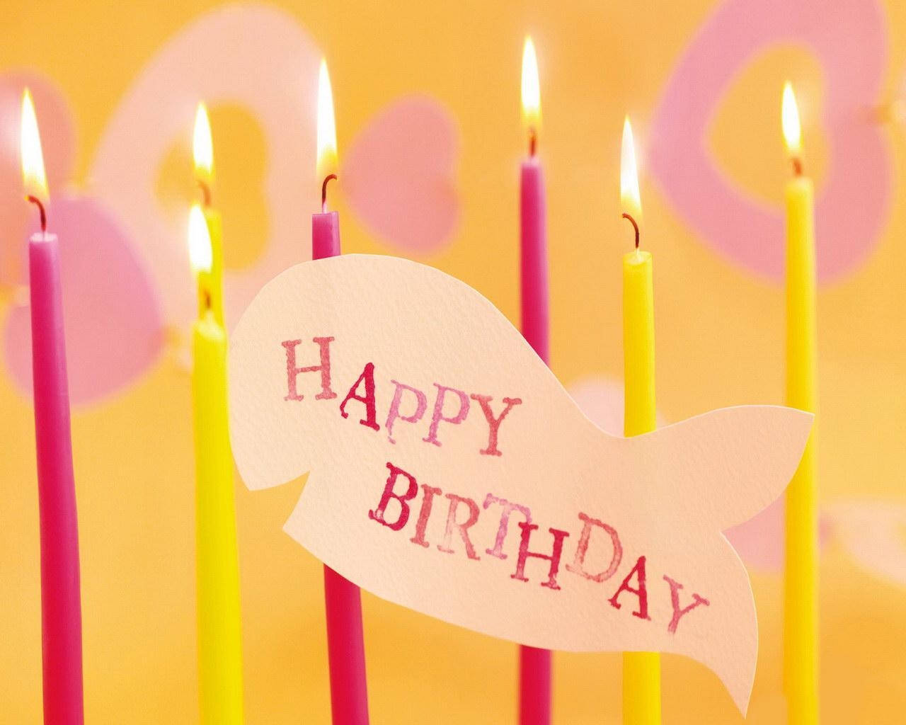 魚形卡片上的Happy Birthday訊息，配有點燃的粉紅色和黃色蠟燭。