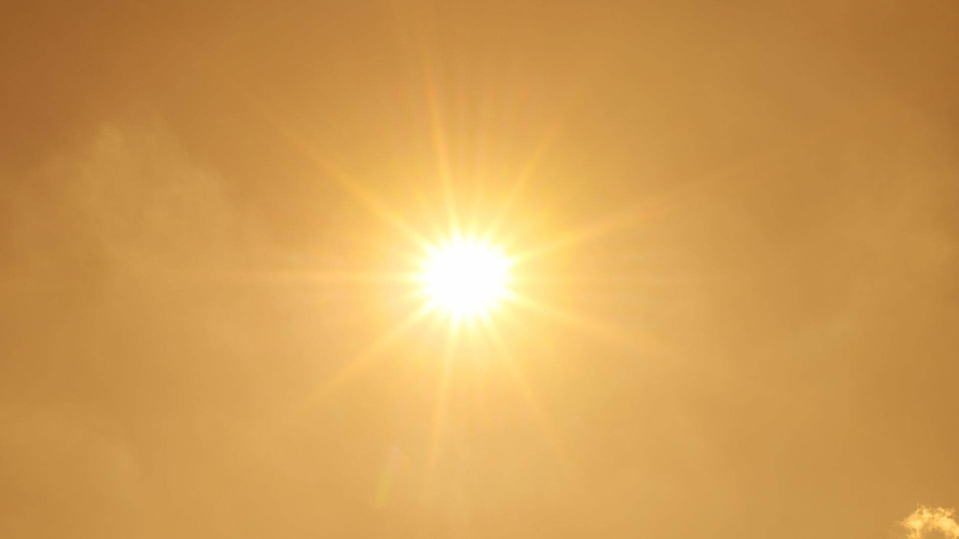 明亮陽光熱力 壁紙 — 一道燦爛的陽光穿透朦朧的琥珀色雲層，在天空中投射出耀眼的星芒。