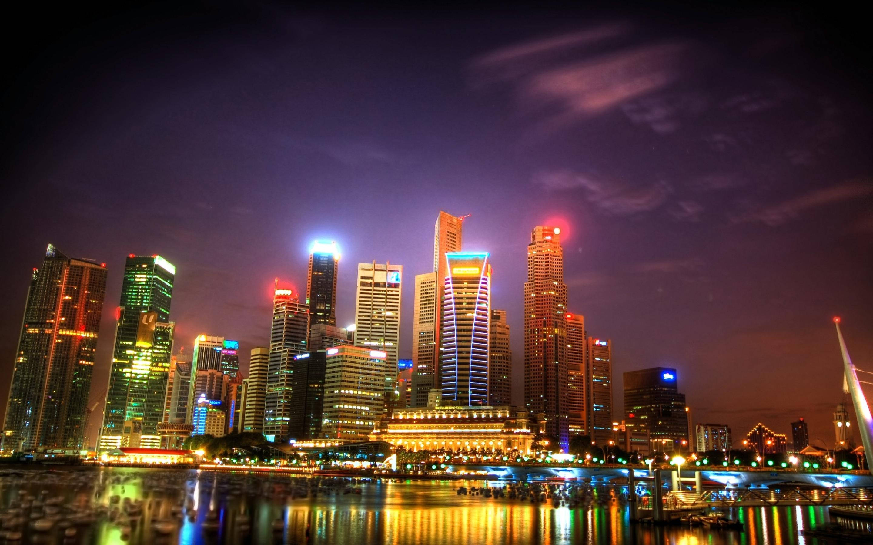 明尼蘇達城市夜景 壁紙 — 令人眼花繚亂的夜景城市景觀，高聳的摩天大樓閃爍著鮮豔的霓虹燈光，倒映在平靜的水道上。