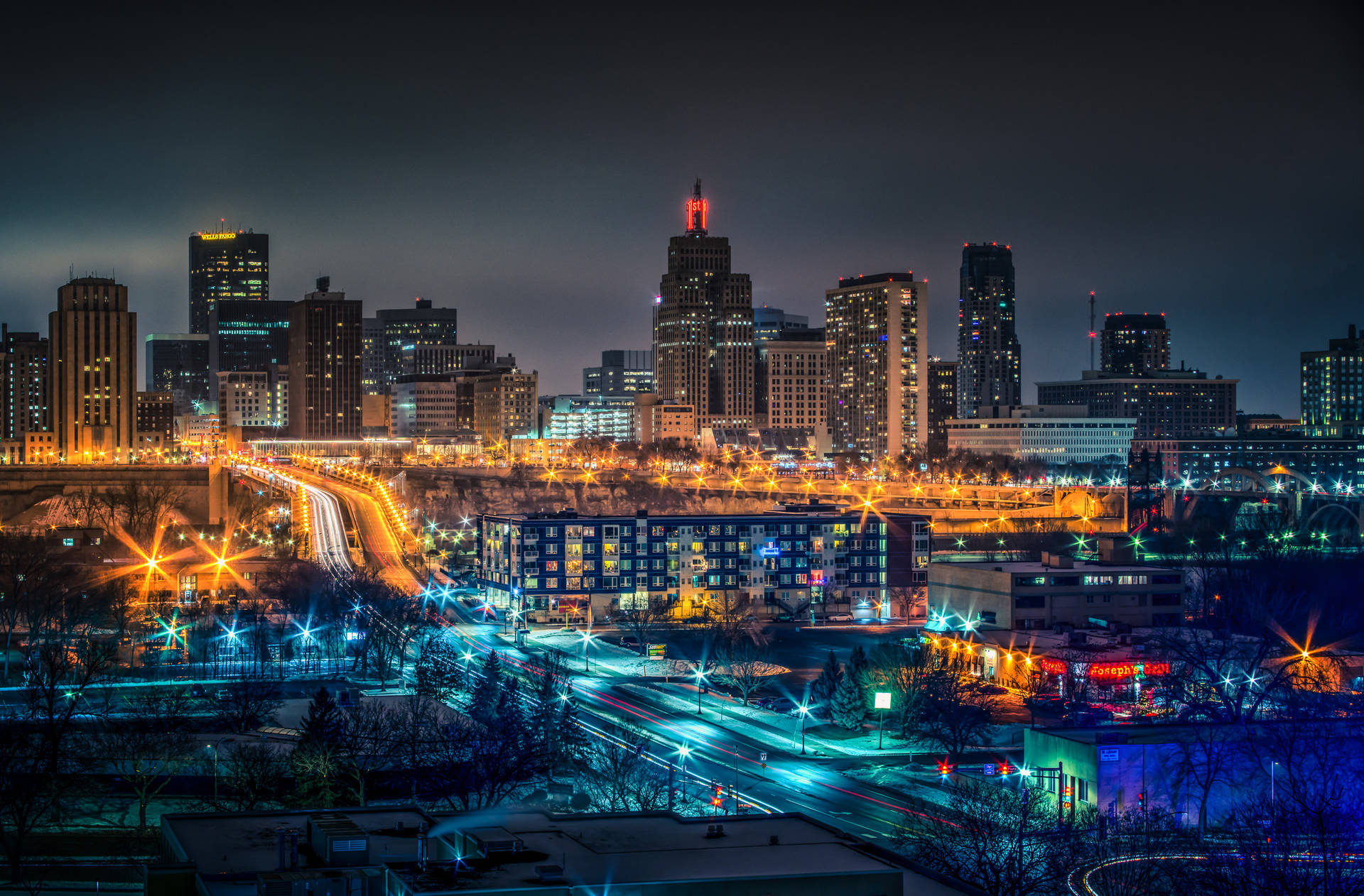 明尼蘇達州聖保羅夜景 壁紙 — 充滿活力的夜景城市景觀，閃爍的摩天大樓和流動的交通燈光點亮城市天際線。