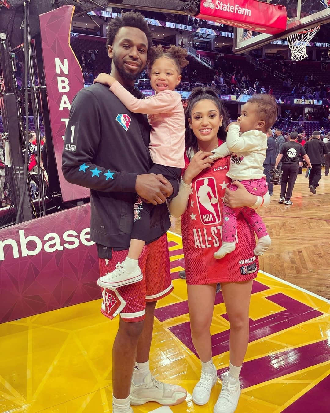 NBA球員和妻子在籃球場上抱著女兒。