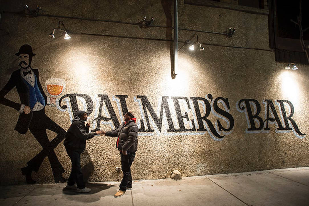 明尼阿波利斯 Palmer's 酒吧壁畫 壁紙 — 夜晚，兩人在溫暖照明的 Palmer's Bar 壁畫前握手。