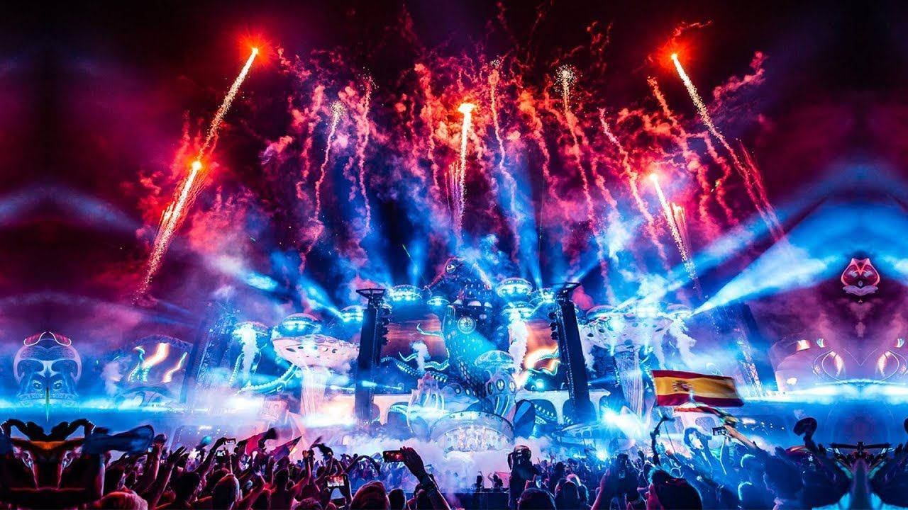 人群在夜間節日中於五彩繽紛的煙火和舞台燈光下歡呼。