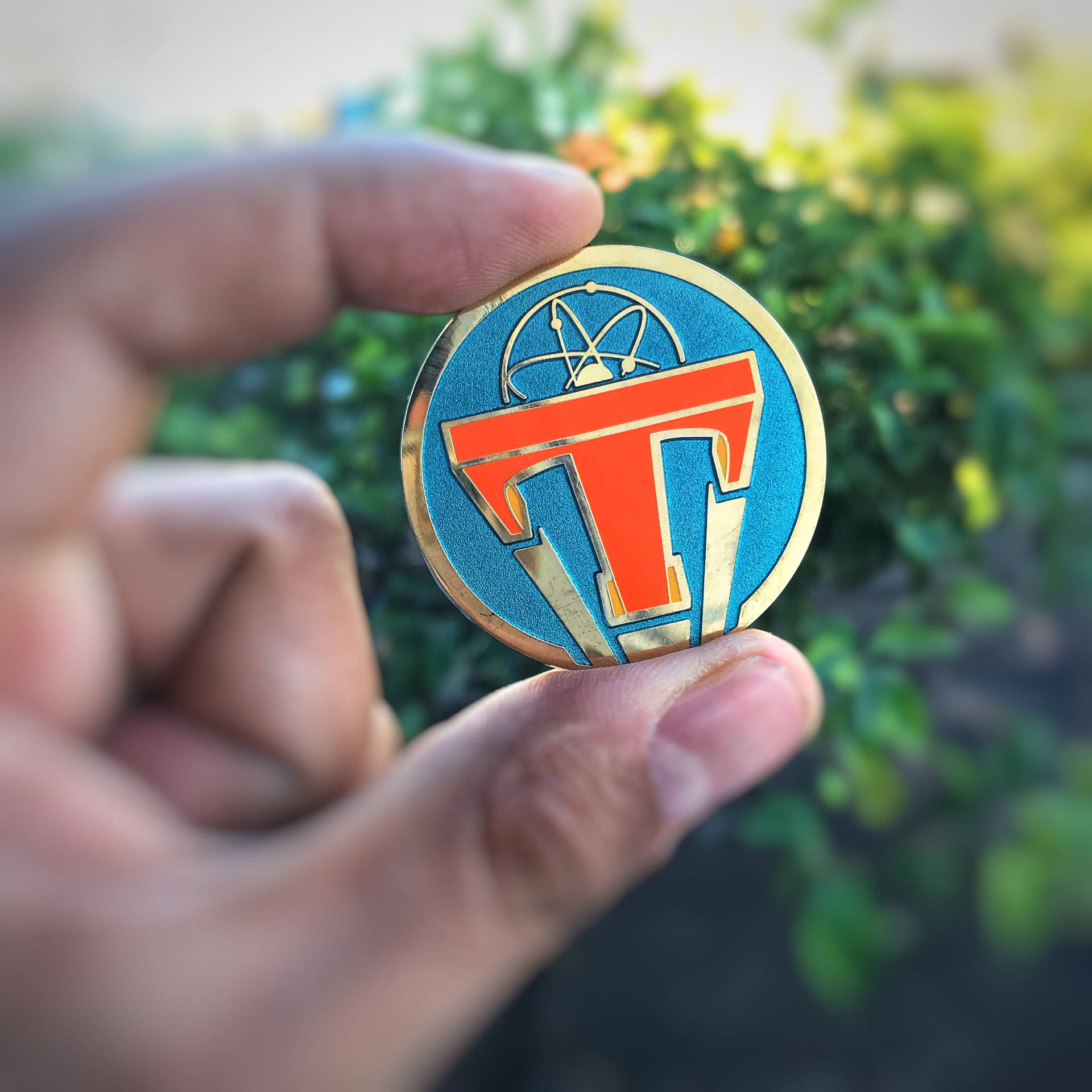 戶外手持帶有原子符號的藍橙金色琺瑯徽章。
