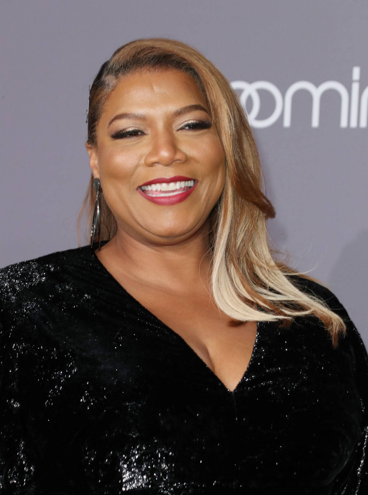 一位在活動中穿著黑色亮片連衣裙微笑的女性。