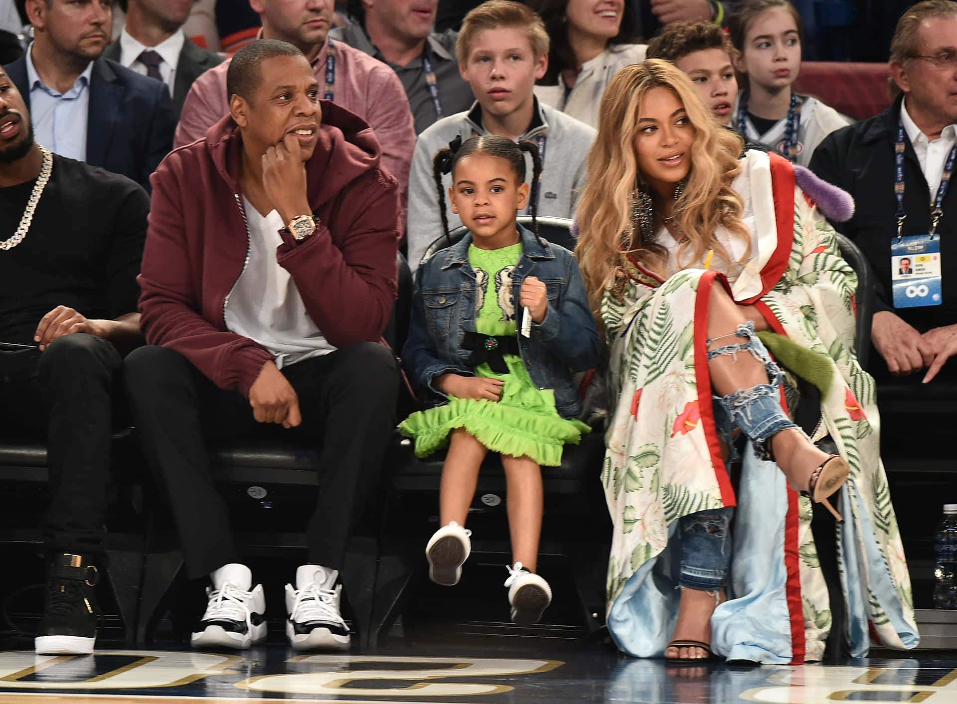 Jay Z、Beyoncé 和女兒 Blue Ivy 坐在籃球場邊。