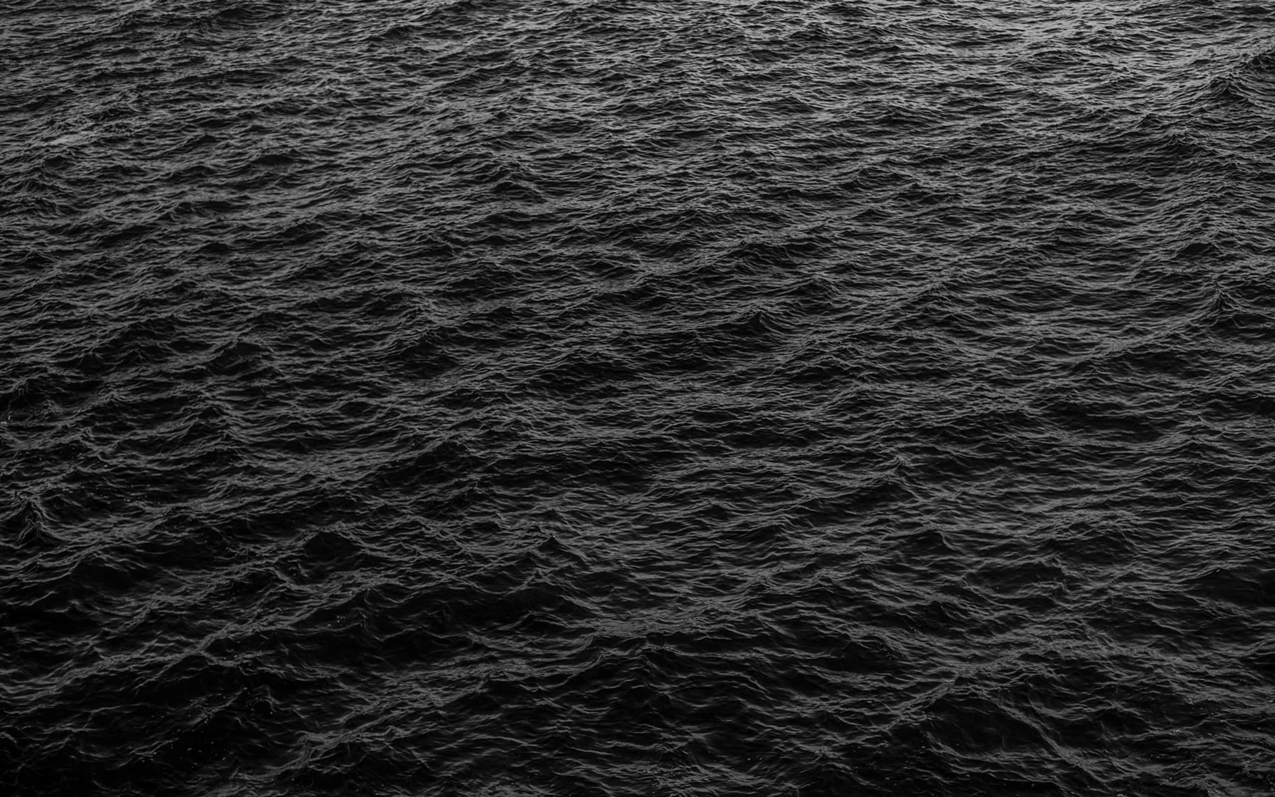 Black And White Ocean 桌布 壁紙 — 昏暗燈光下深色紋理海浪的陰鬱俯視圖。