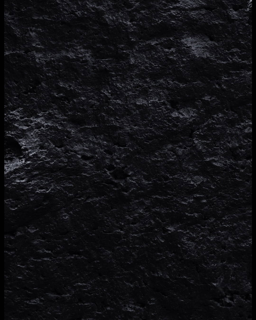 Rocks 桌布 壁紙 — 昏暗燈光下粗糙深色石頭表面的特寫，帶有微妙的紋理變化。