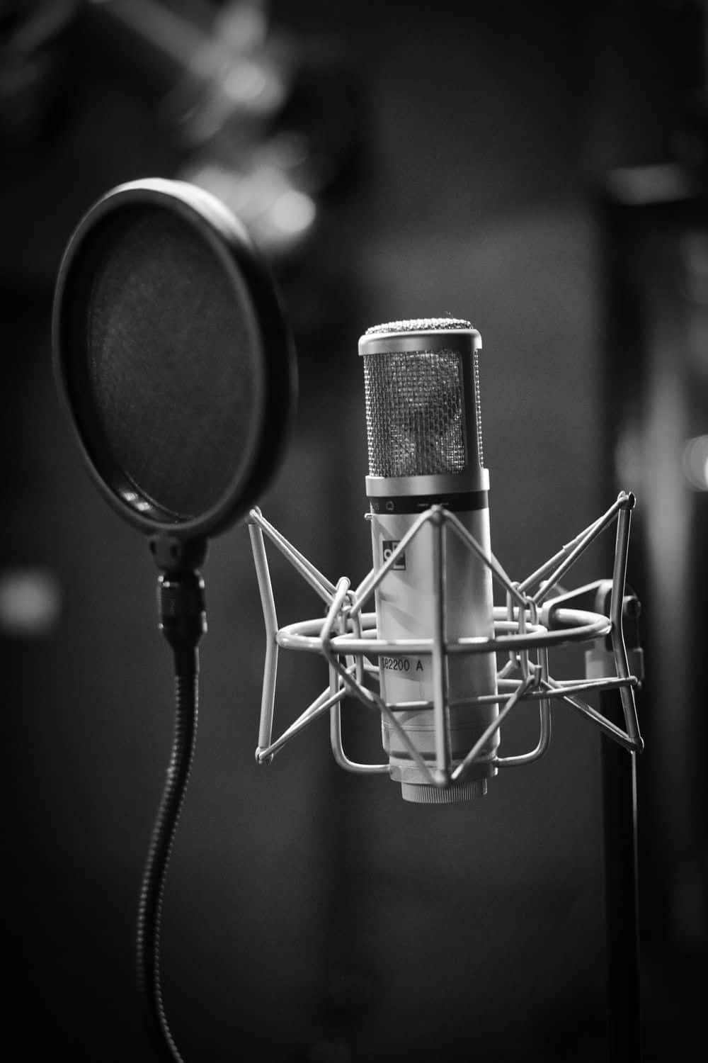 Studio 桌布 壁紙 — 昏暗錄音室內專業錄音室麥克風與防噴罩的黑白特寫。