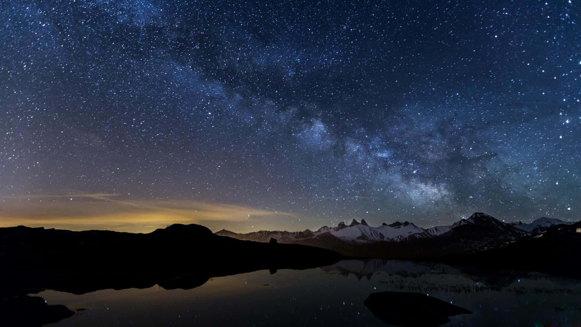 積雪的山峰和湖泊倒映著星空和銀河。