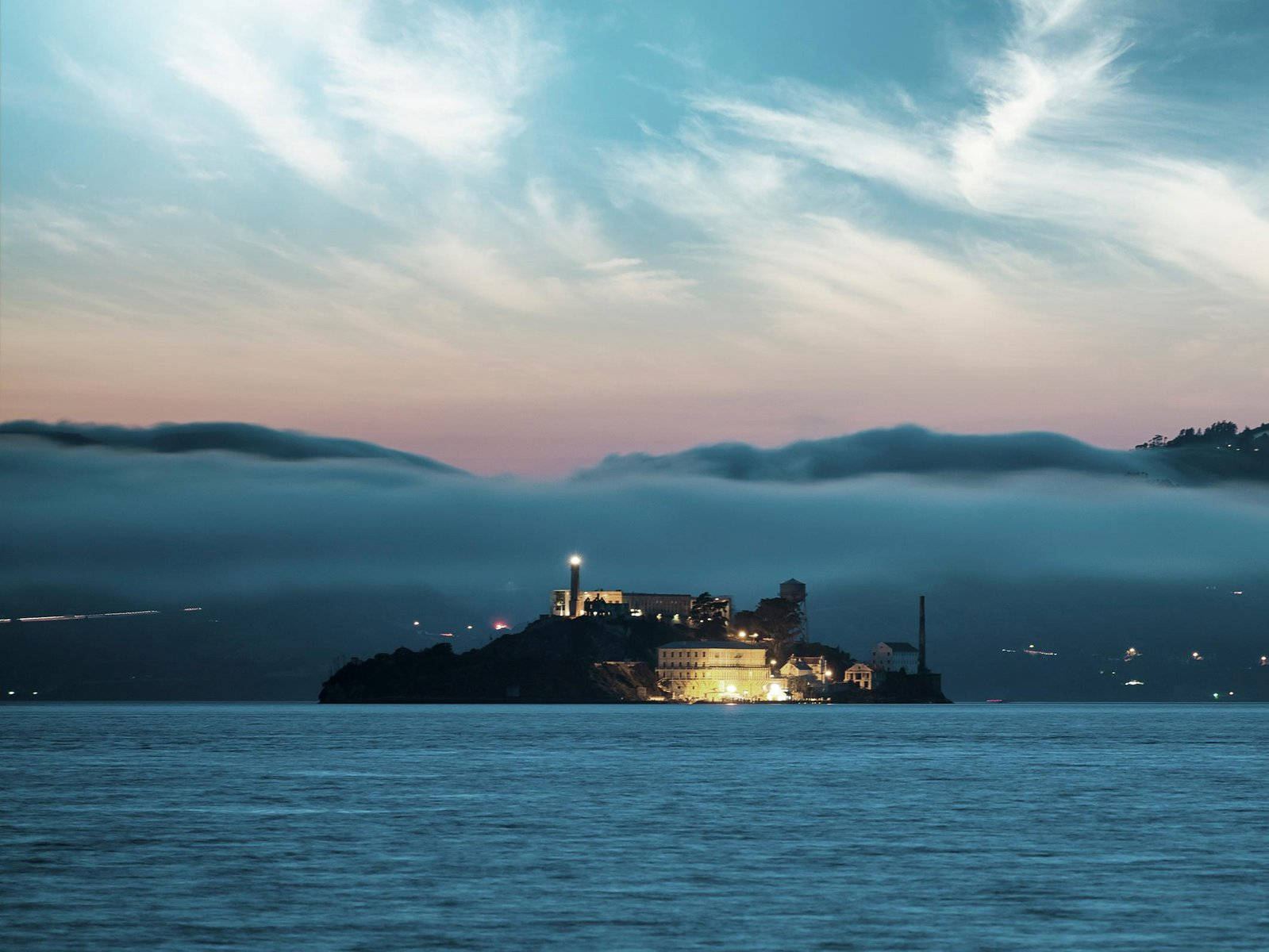 黃昏時分，霧氣籠罩的海灣水域和多雲天空下的惡魔島