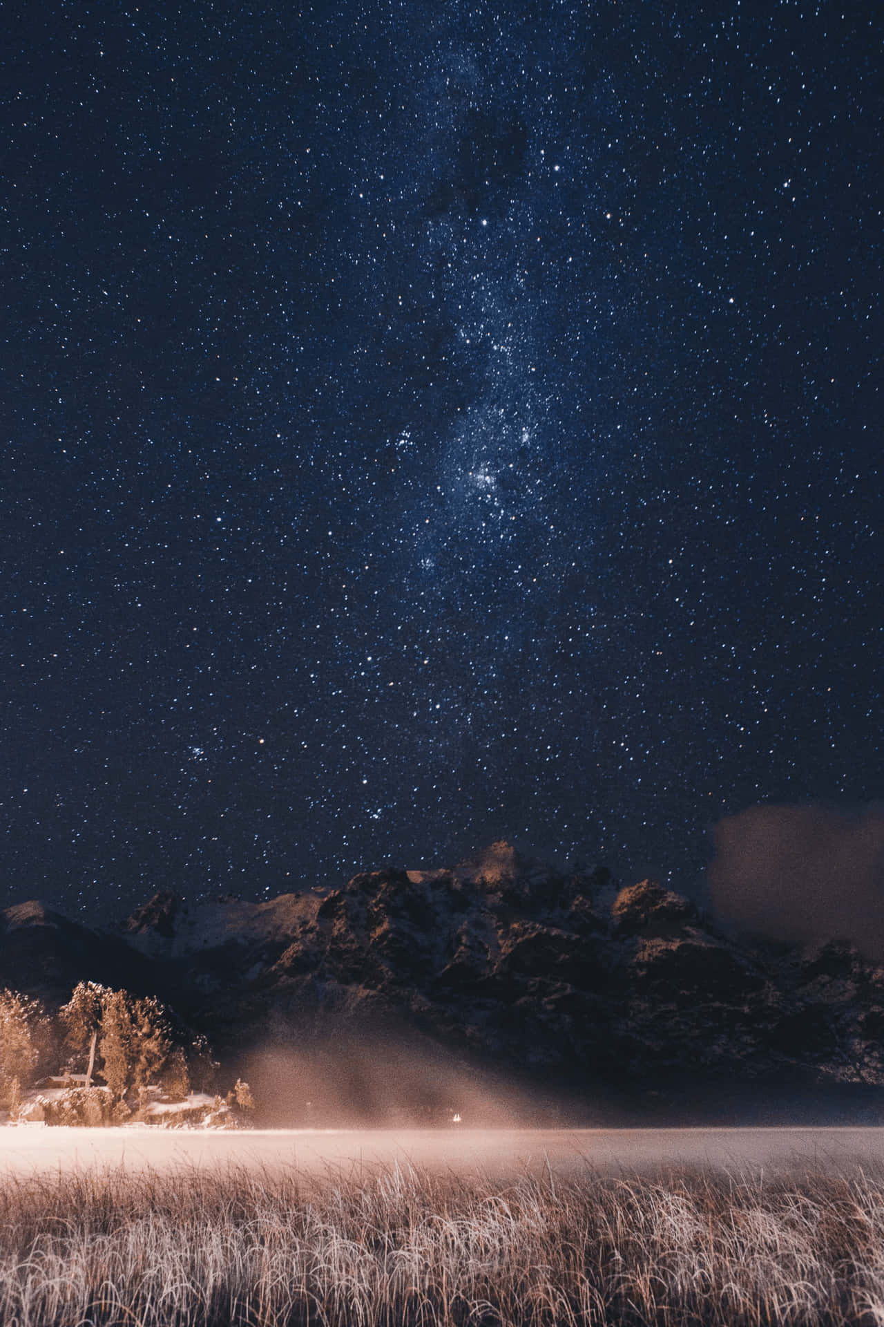 星空下積雪的山峰，草地上有霜