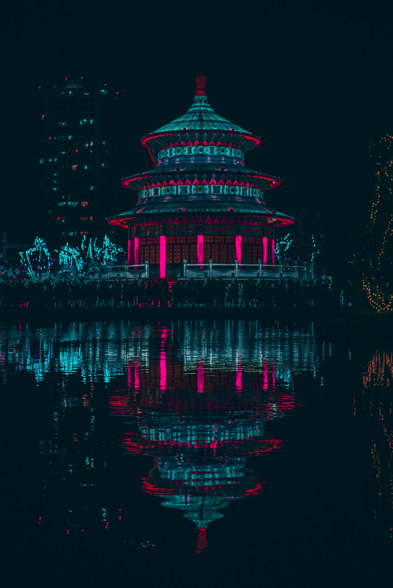 夜間水中倒映的霓虹寶塔，背後城市燈光。