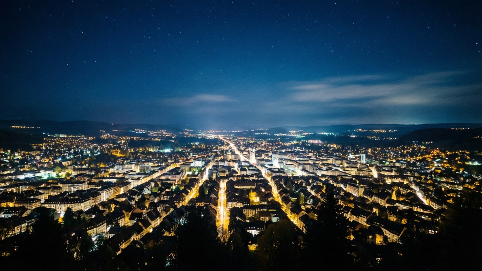 夜晚的城市景觀，發光的燈光和上方的星空。