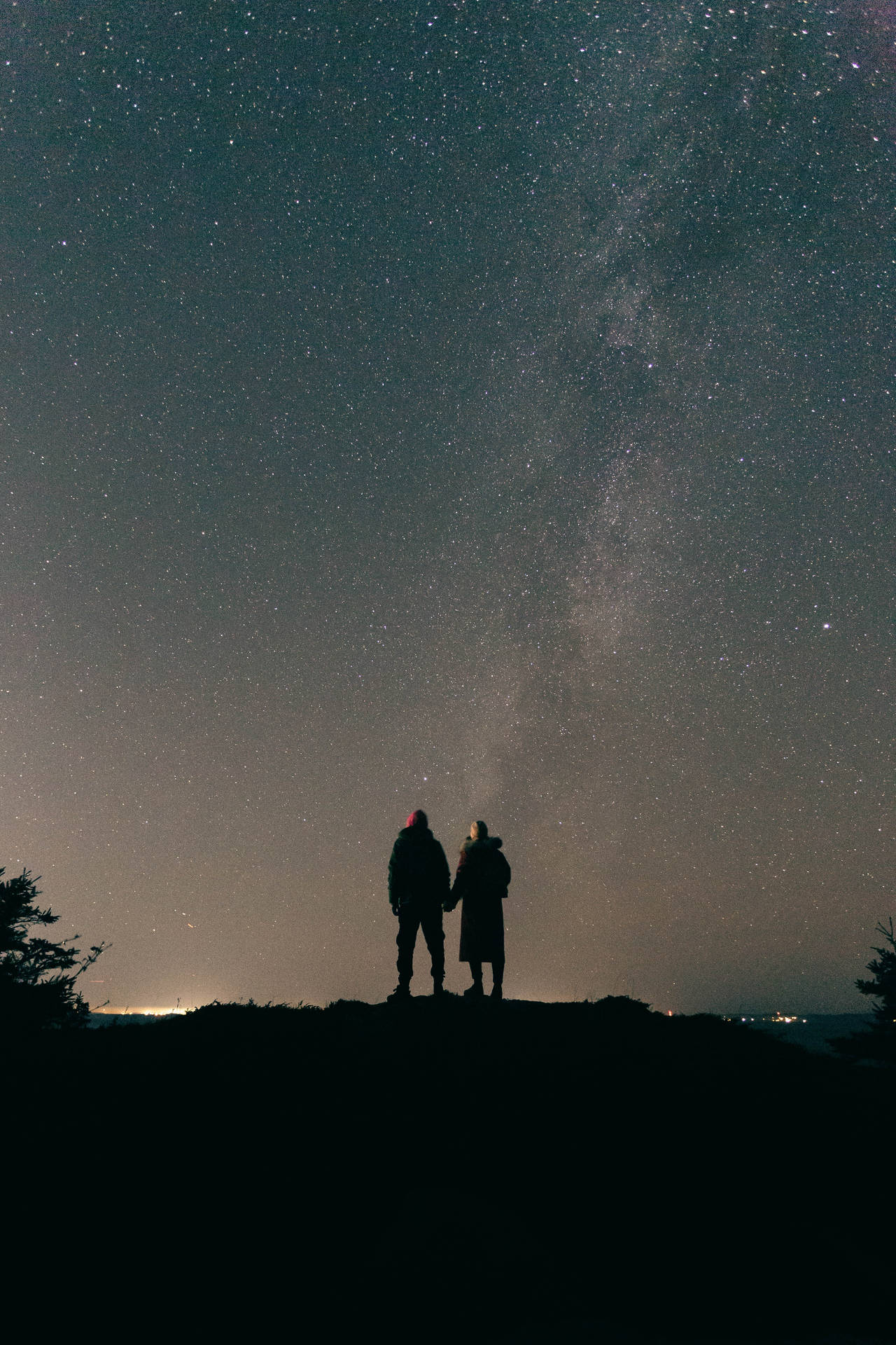 兩個人手牽手，在星空下凝視著銀河。