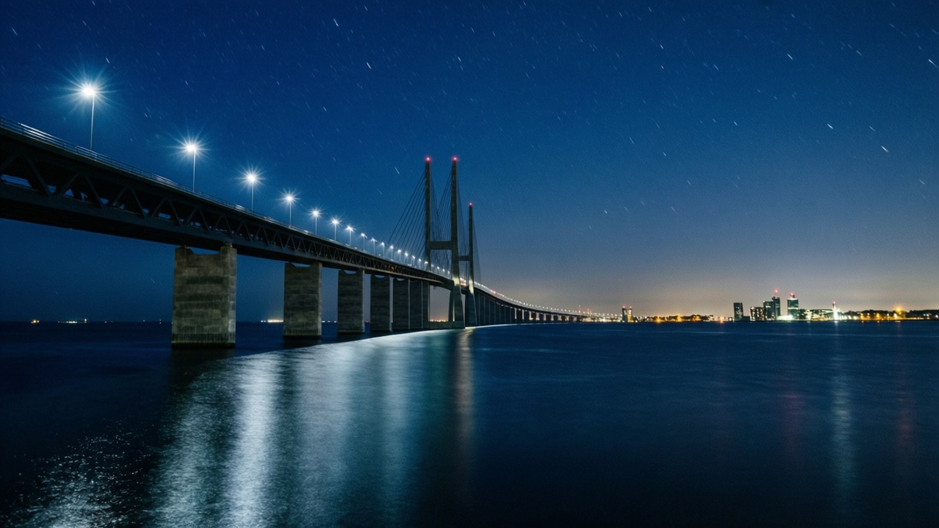 夜晚在水面上的照明吊橋，背景有星星和城市燈光。