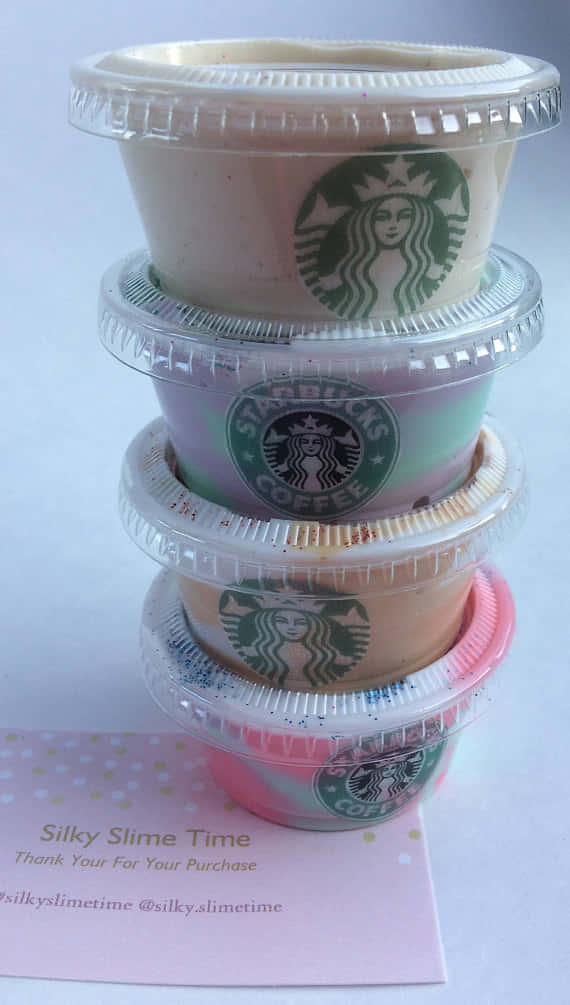 星巴克史萊姆杯圖像 壁紙 — 疊起的Starbucks星冰樂杯子，帶有彩色漩渦和閃粉，放在粉紅色圓點卡上。