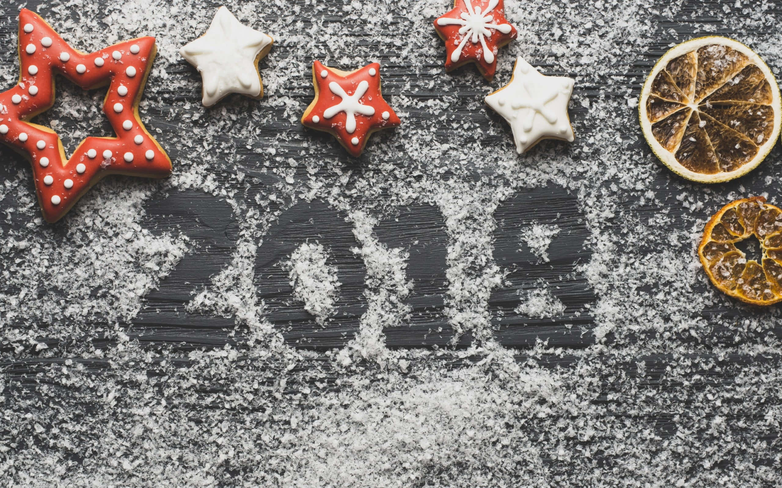 2018 桌布 壁紙 — 星形曲奇和乾橙片圍繞著用糖粉寫在深色紋理表面上的2018年。