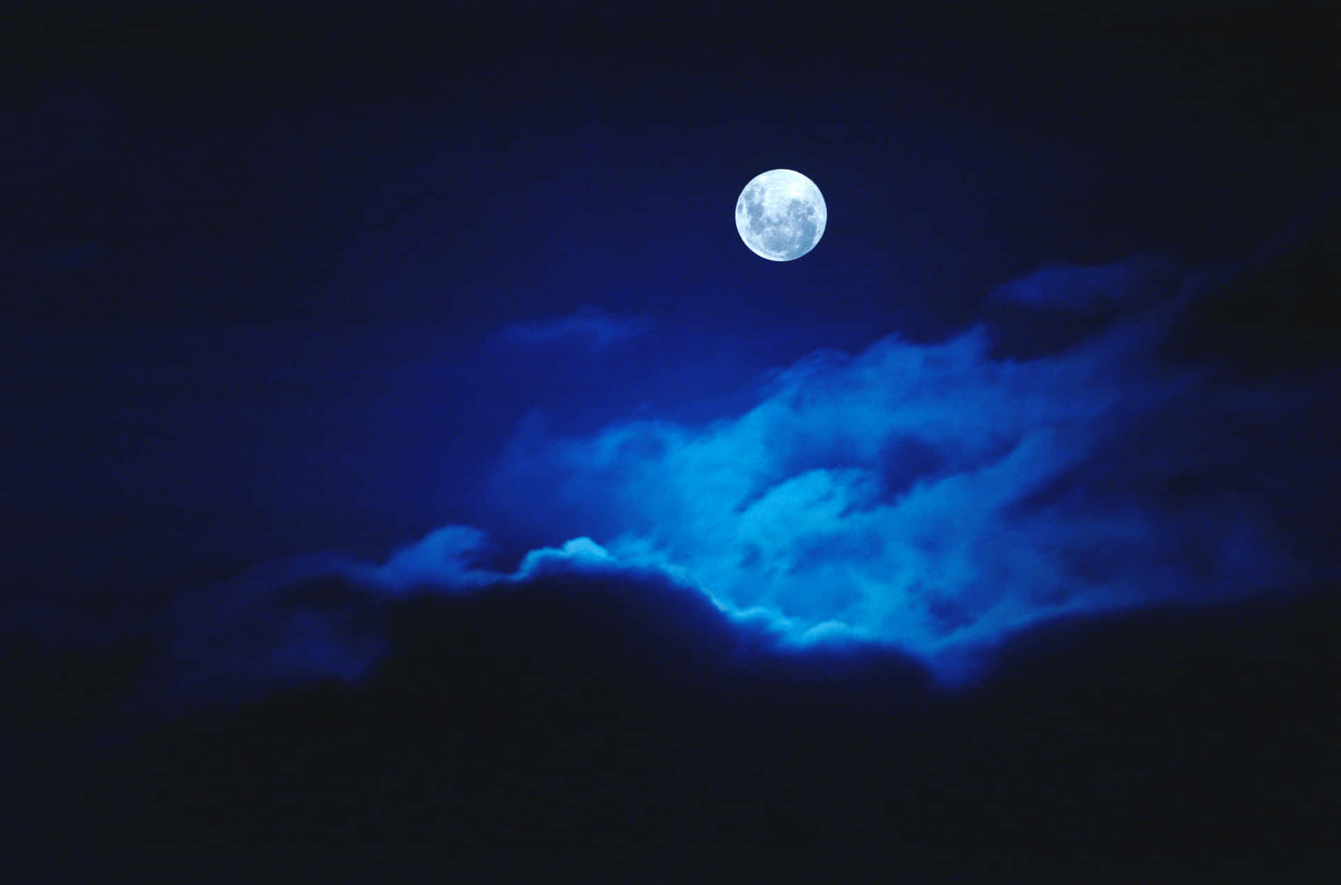 滿月透過深藍色雲層在夜晚閃耀。
