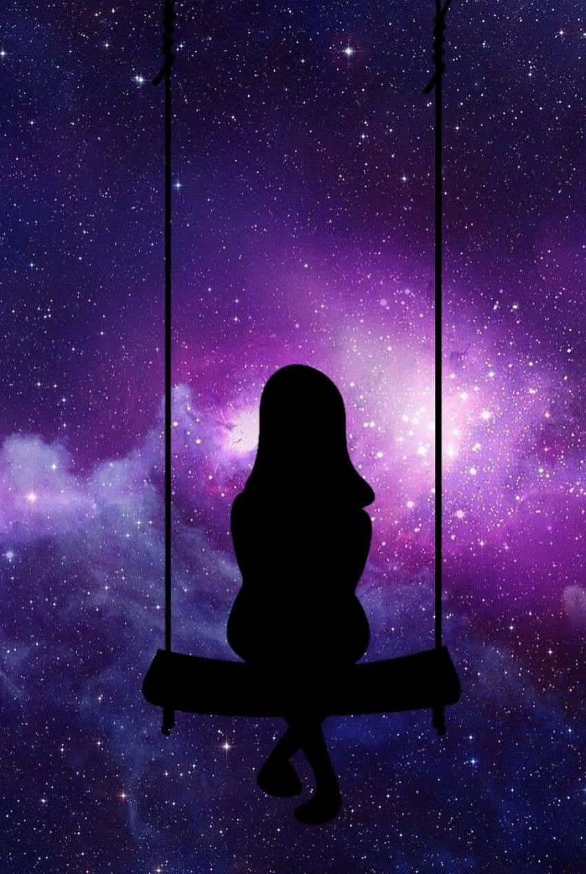 星河動漫坐鞦韆女孩 壁紙 — 一個人的剪影獨自坐在鞦韆上，懸掛在充滿活力的紫色和藍色星空銀河天空前。