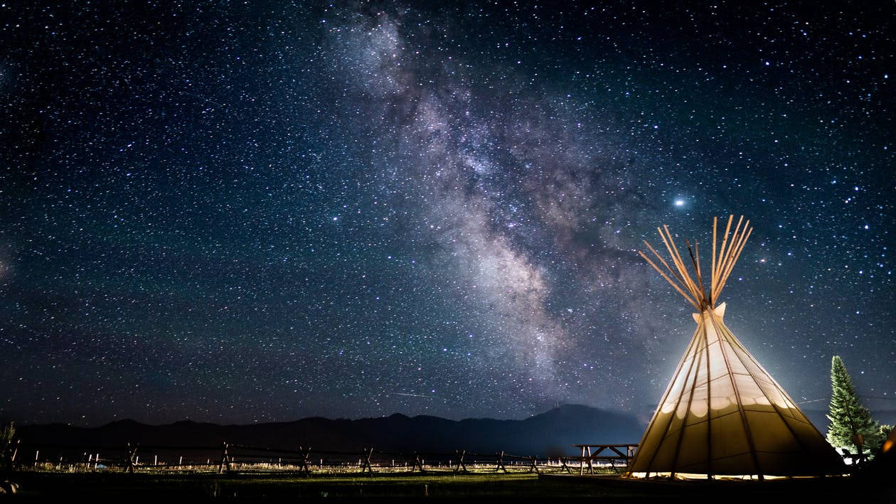 在繁星點點的夜空下，一個發光的帳篷，銀河清晰可見。
