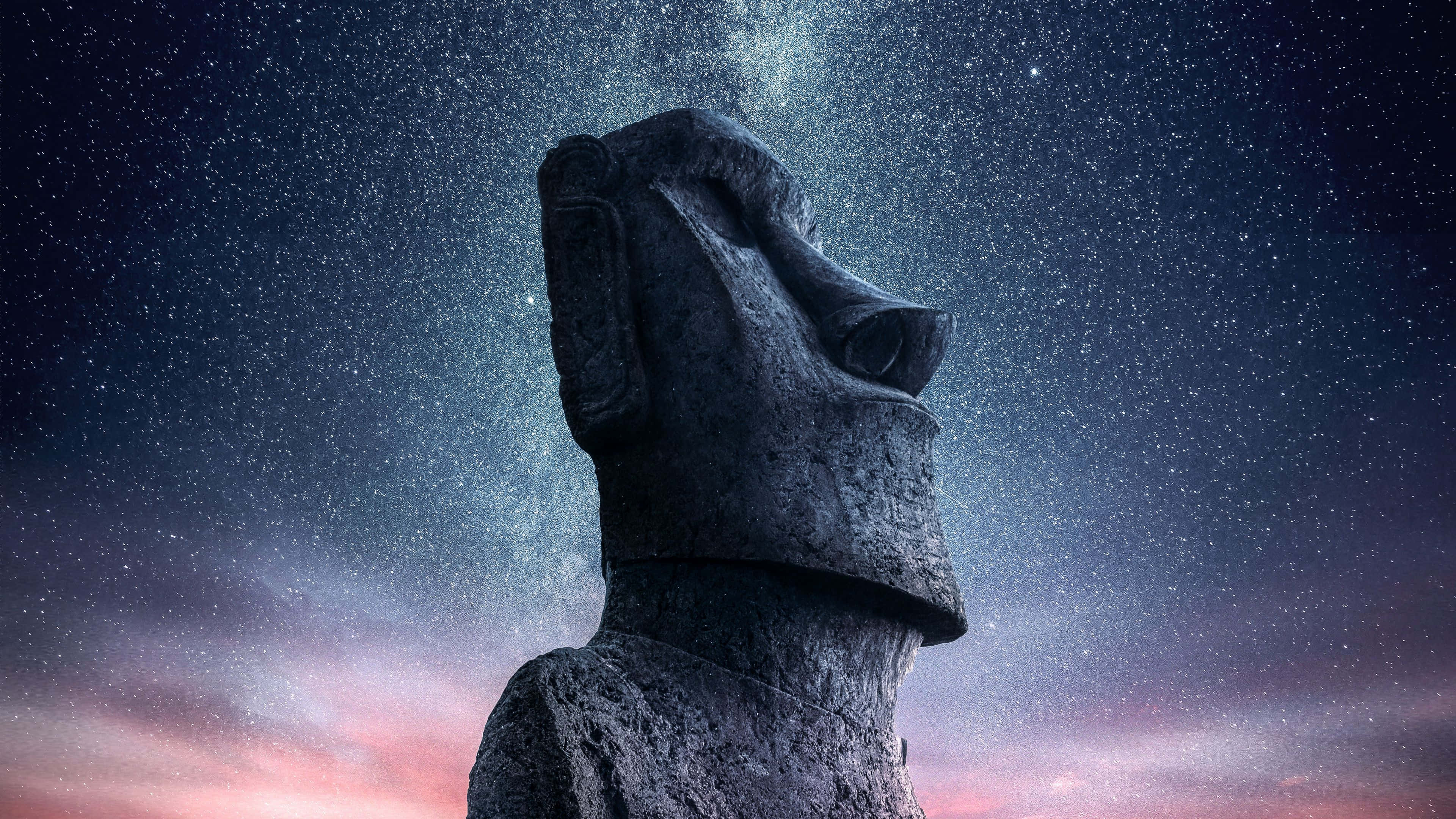 星空下的摩艾石像 壁紙 — 一座雄偉的摩艾石像在繁星點點的夜空下仰望，頭頂有宇宙塵埃旋轉。