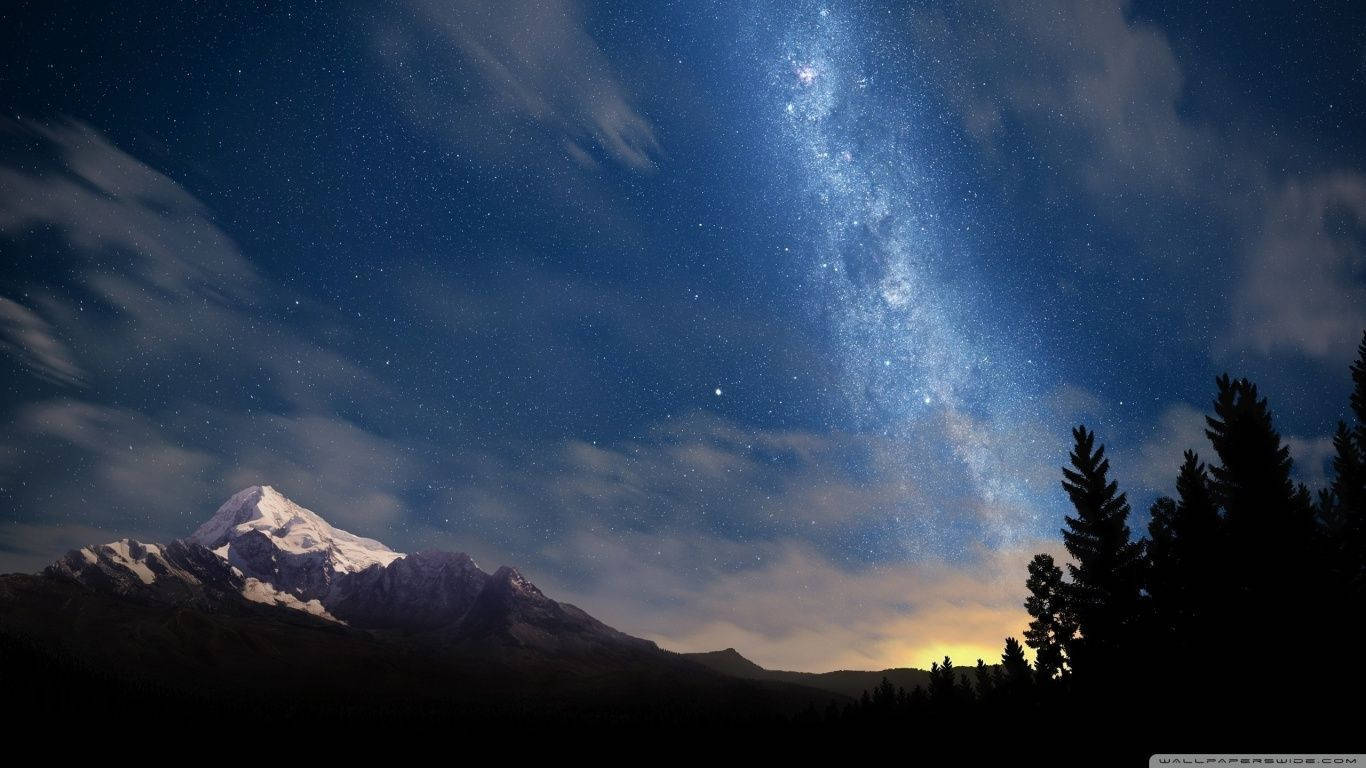 在星空夜空下，白雪覆蓋的山脈，銀河清晰可見。