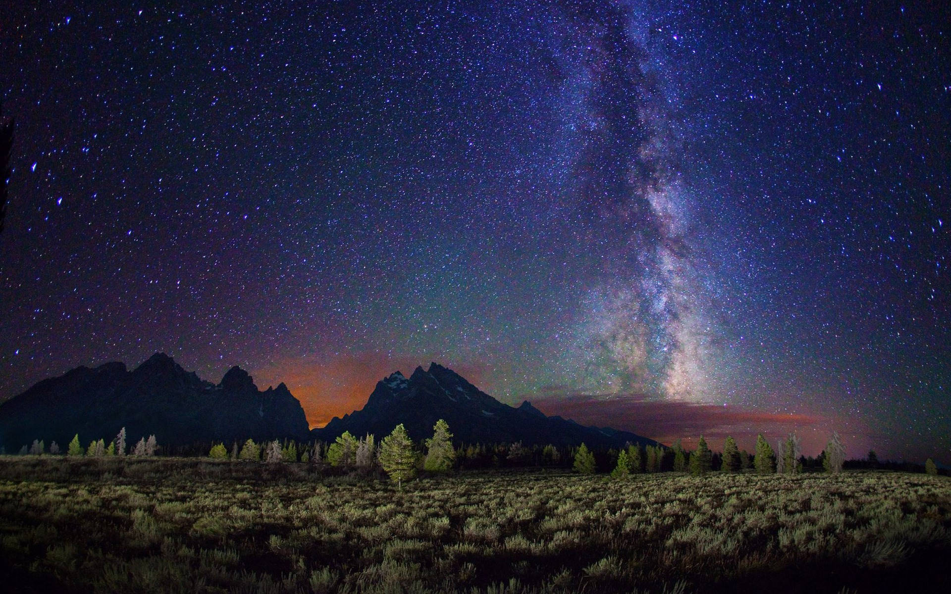 星空下的自然風景高清壁紙 壁紙 — 銀河系在繁星點點的夜空下，在崎嶇的山峰上燦爛地拱起。