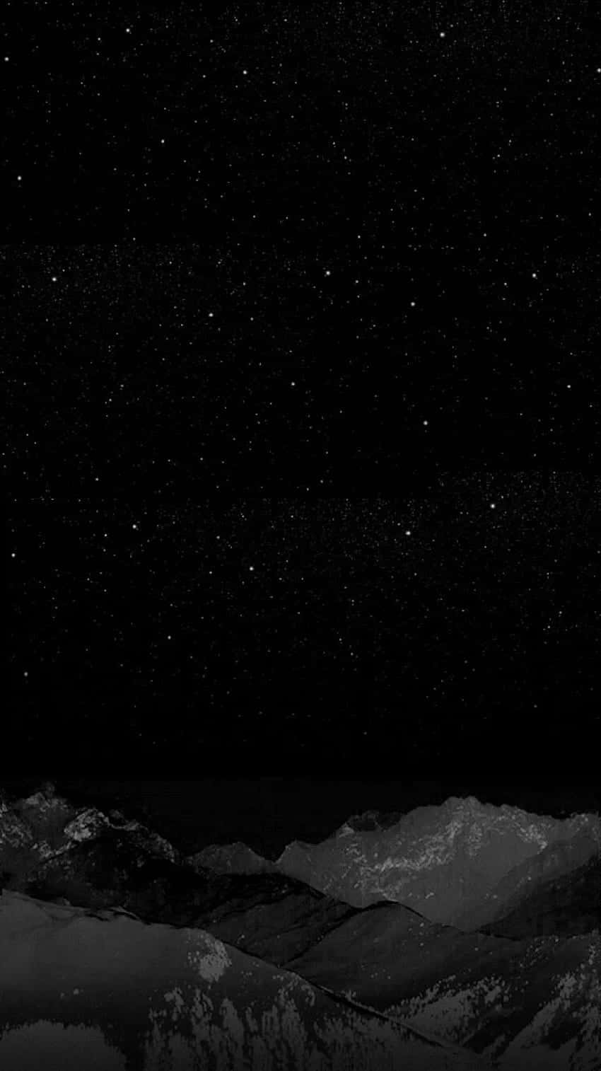 星空下的雪山 壁紙 — 單色星空拱起在崎嶇的山脈之上，山頂覆蓋著白雪。