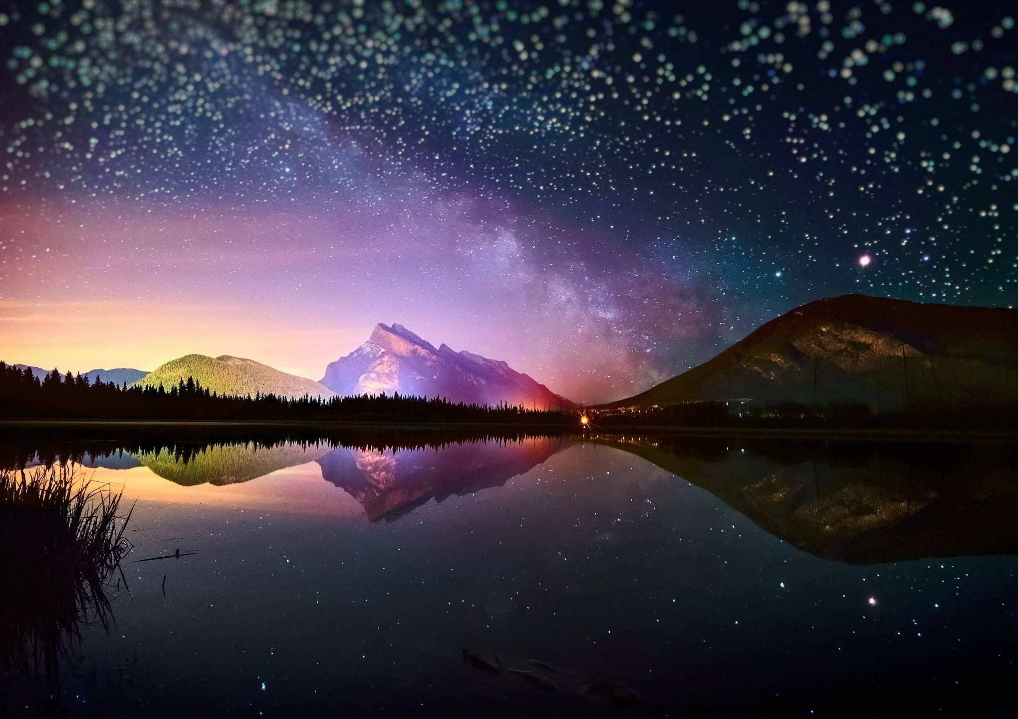星空倒影於山湖高清壁紙 壁紙 — 繁星點點的夜空，銀河拱跨平靜的湖面，倒映著山巒和鮮豔的暮色。