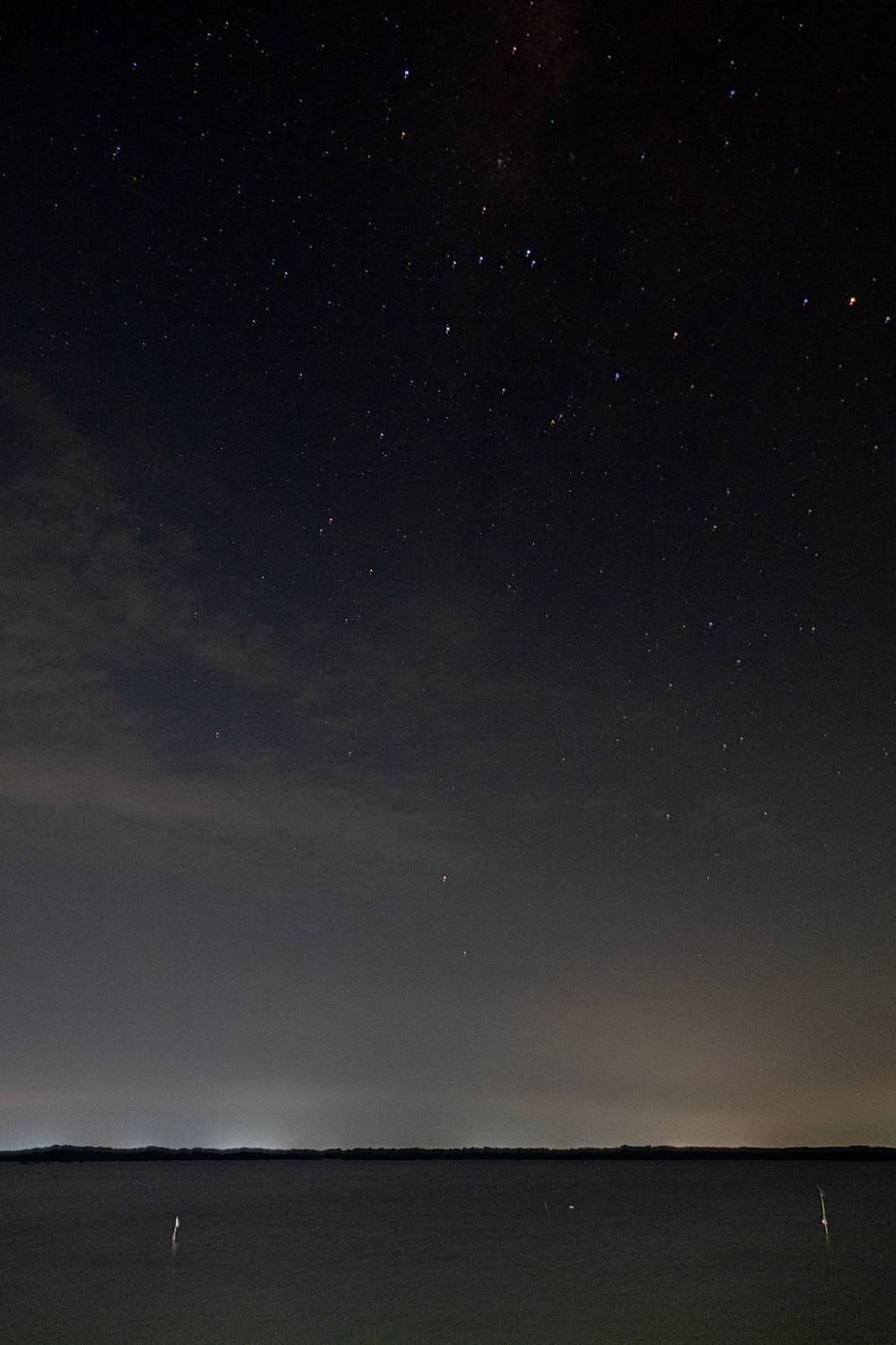Landscape 桌布 壁紙 — 星空夜空在平靜的深色水天際線上拱起，帶有微弱的雲和遠處的燈光。