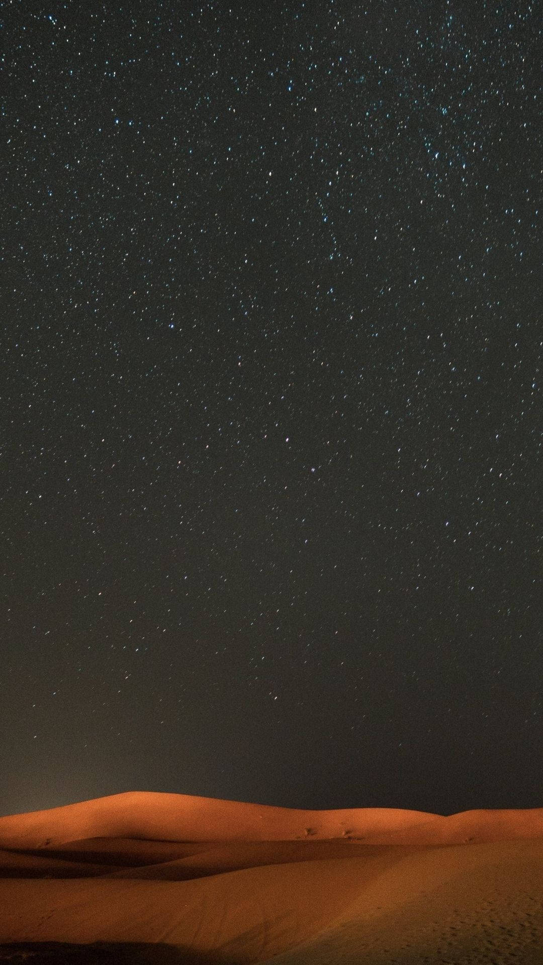 View 桌布 壁紙 — 星空夜空覆蓋著廣闊的沙漠，下方有發光的橙色沙丘。