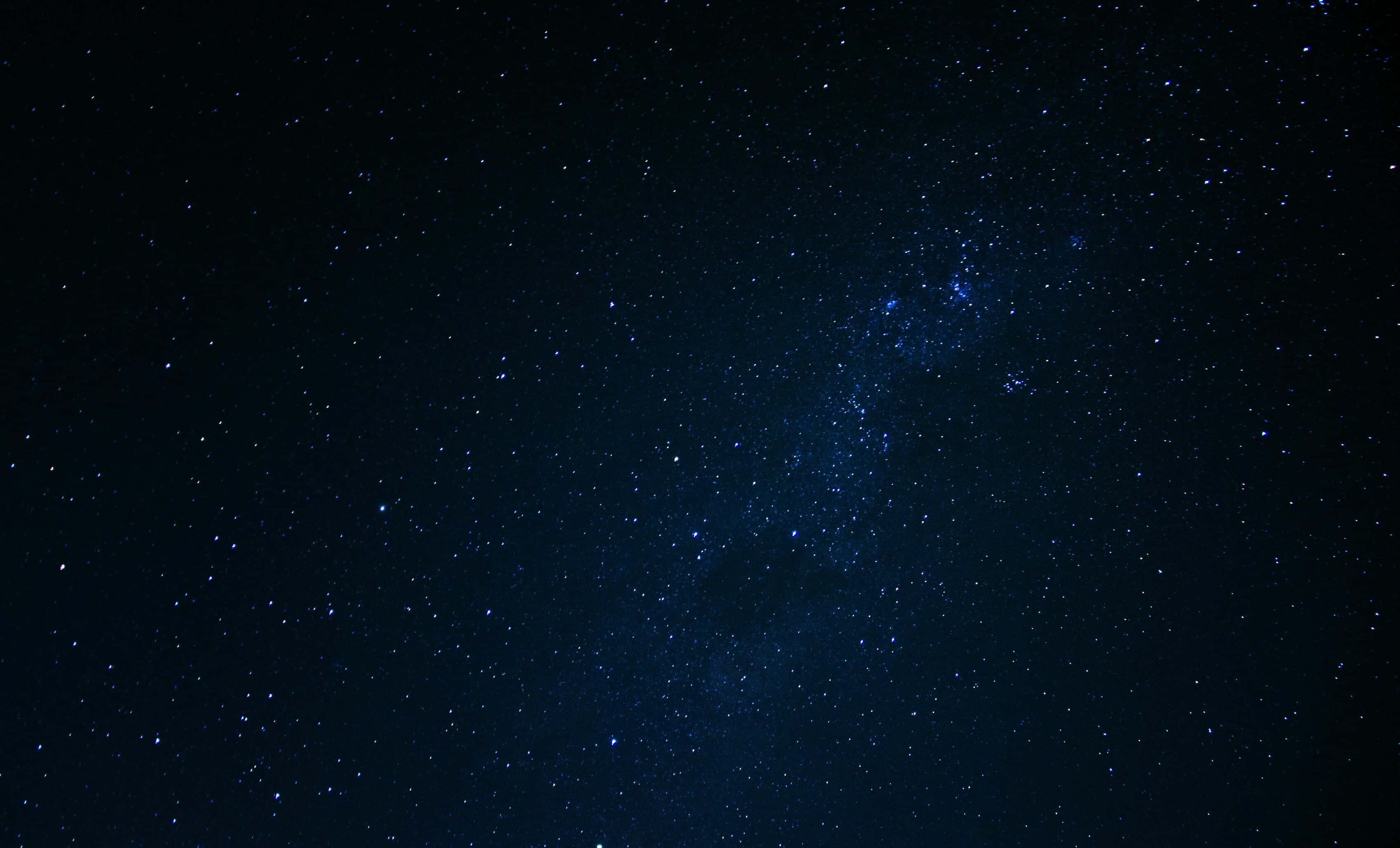 星空背景：空間中的光點 壁紙 — 令人嘆為觀止的銀河系景觀，藍色星星在深邃的宇宙夜空中閃耀。