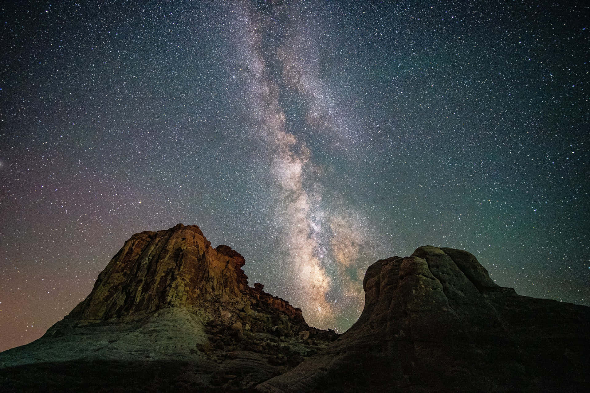 銀河系在繁星點點的夜空下，拱起於沙漠岩石地貌之上。